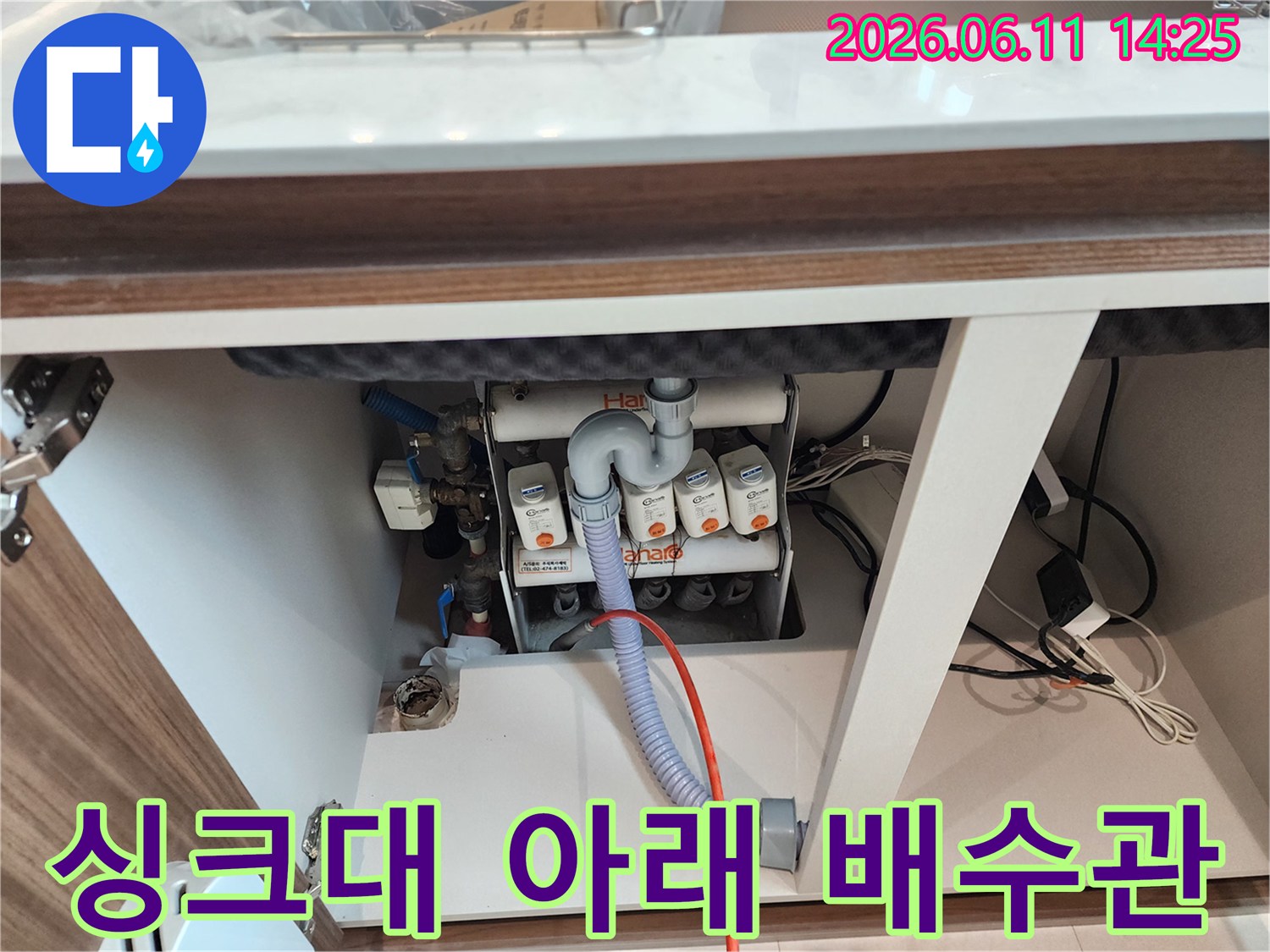 싱크대 하부장 내부에 노출된 밸브와 분기된 배수 배관의 모습입니다.