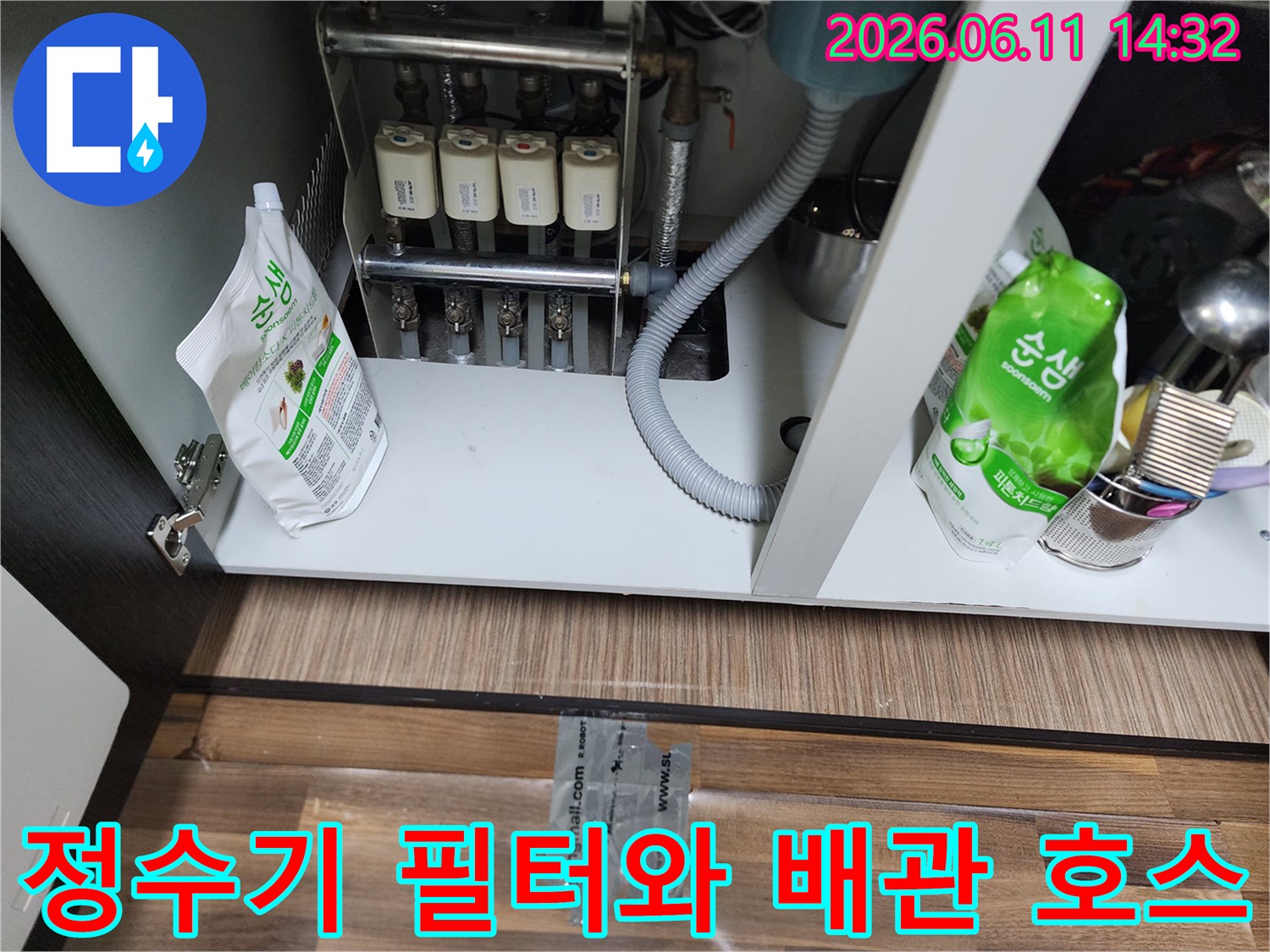 싱크대 하부장 내 정수 필터와 연결된 굵은 배관 호스 상세 사진