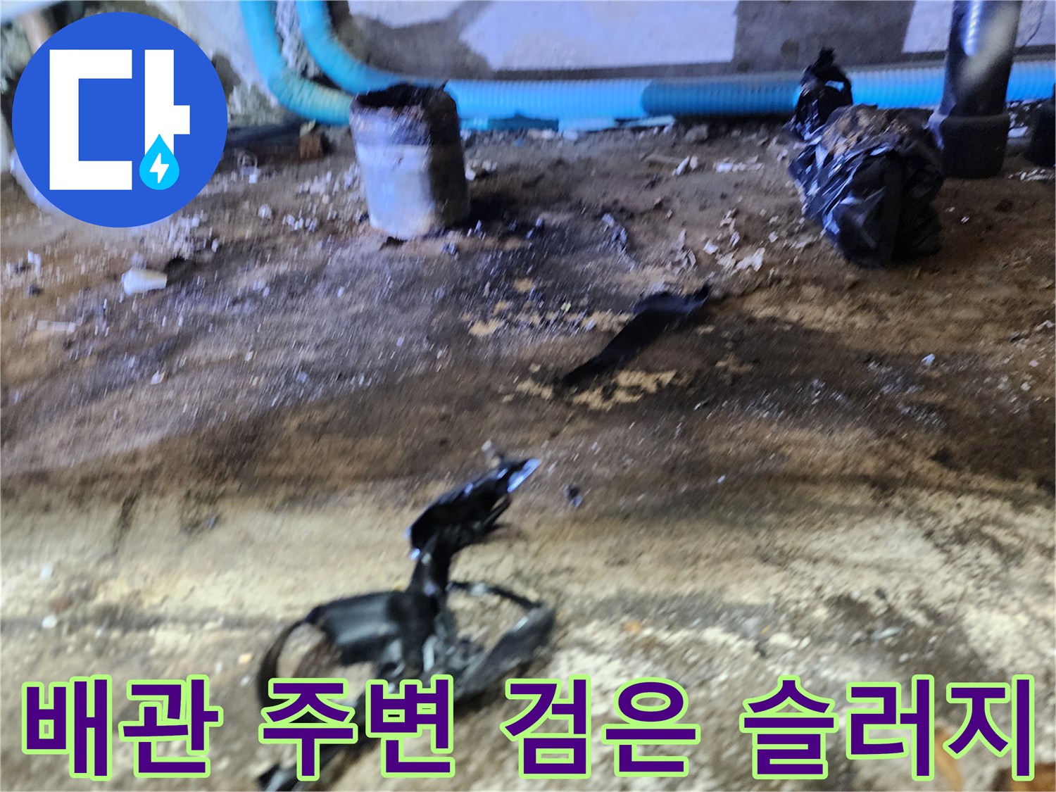 검게 오염된 바닥과 배관 근처에 떨어진 이물질 조각들