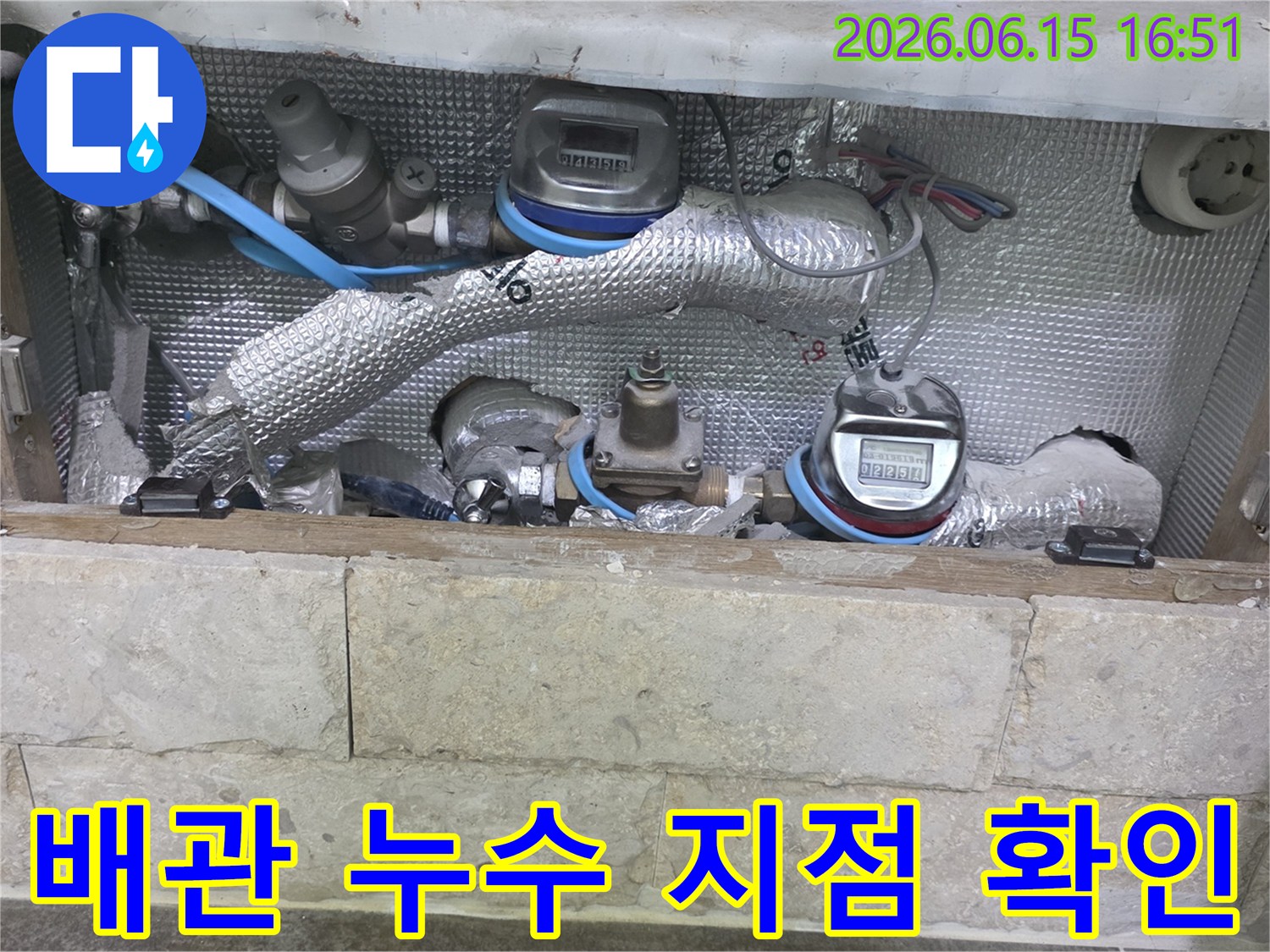 은색 단열재로 덮인 배관과-여러 개의 수도 계량기가-설치된 공간에서-누수 지점을 찾는 모습입니다
