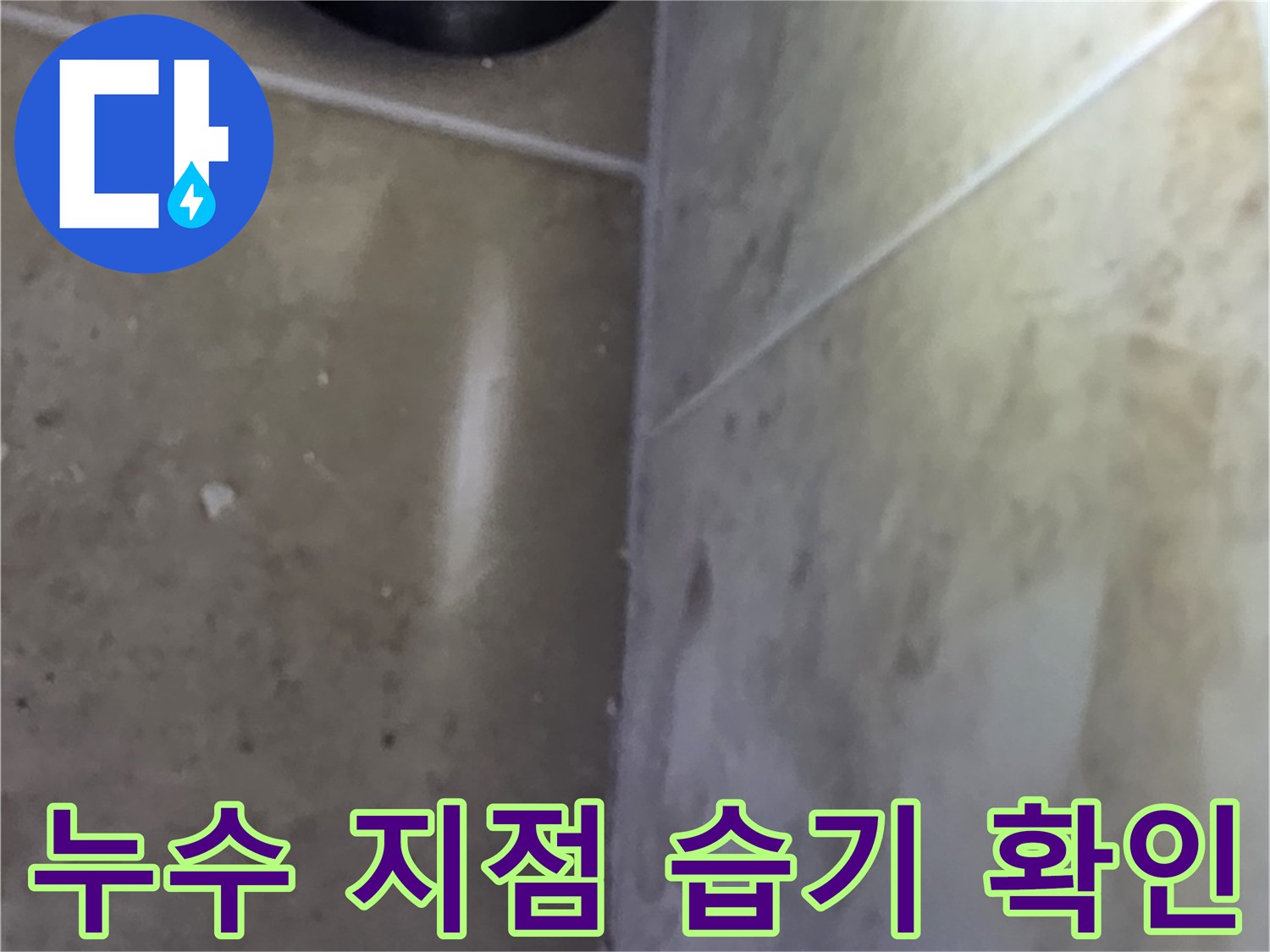타일 바닥과 벽면의 접합부에서-습기가 감지되어 누수 지점을 파악하는 모습