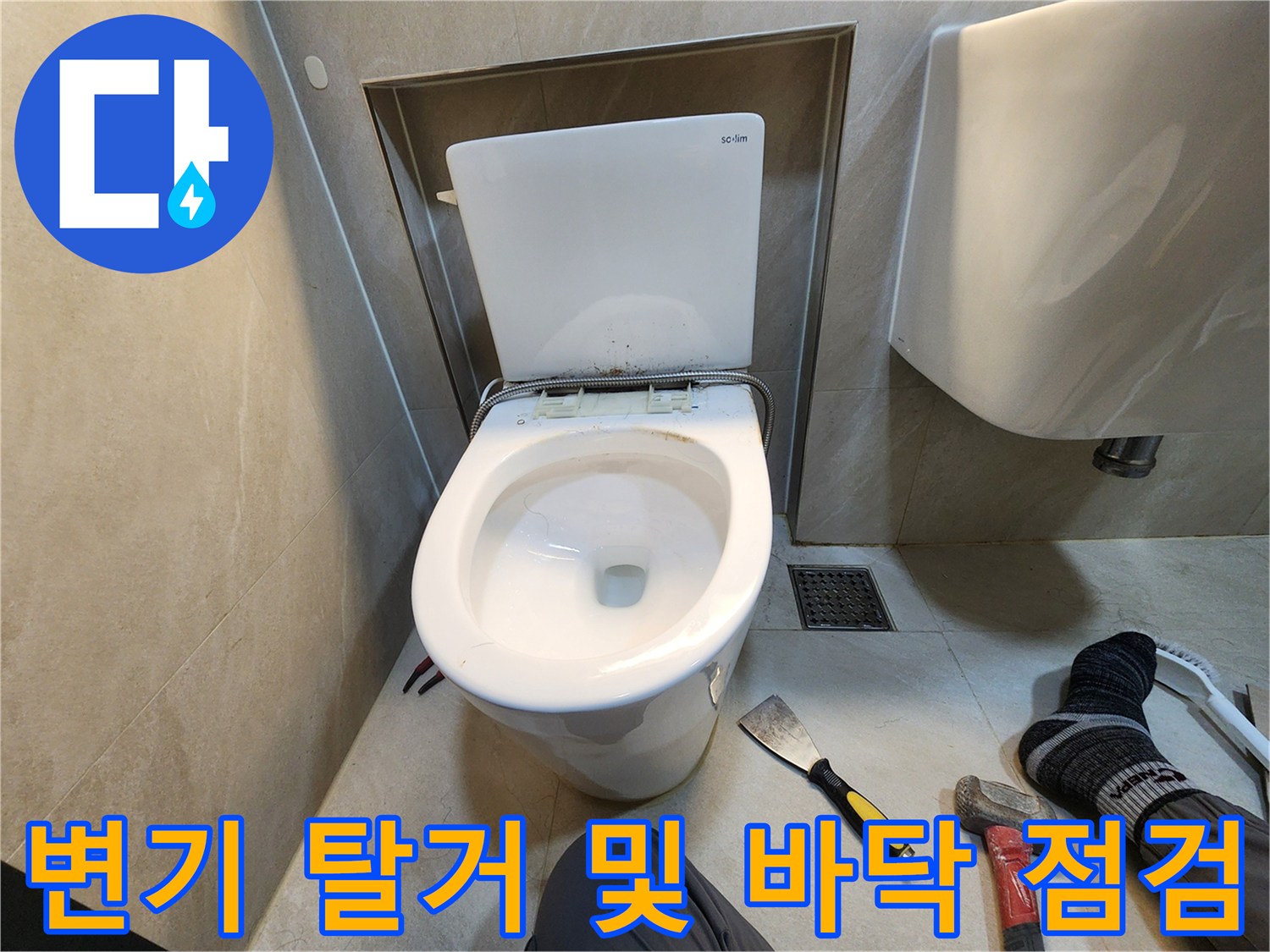 양변기를 제거한 후 노출된 하수관과 작업 도구의 모습