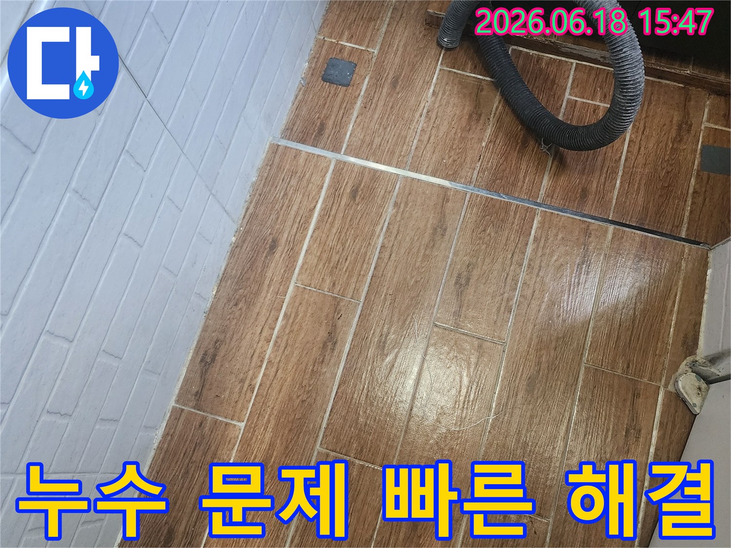 염창동 아파트에서 누수 문제를 빠르게 해결하기 위한 탐지 작업이 진행 중인 현장 사진입니다-바닥 타일 위에 검은색 호스가 놓여 있습니다.