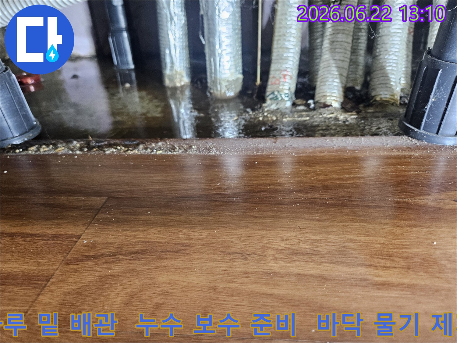 마루 밑-배관에서-물이-새어-나와-고여있는-모습을-보여주며-보수-작업-전-사진