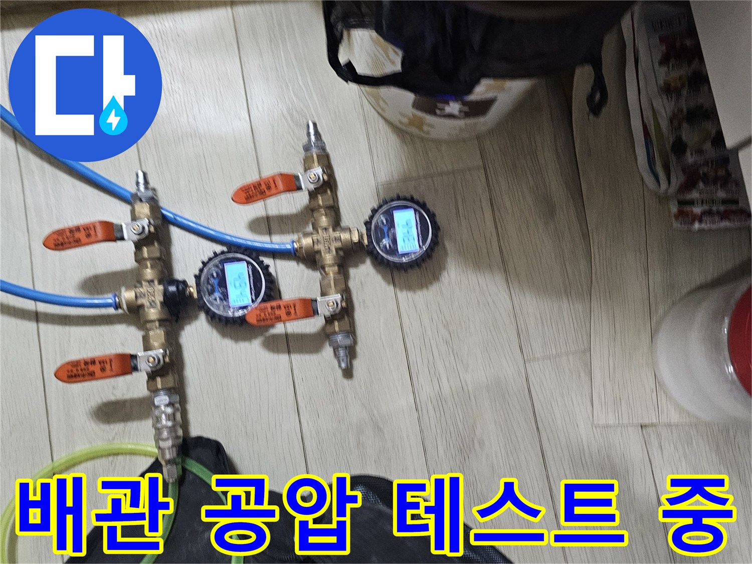 배관 연결 부위에 설치된 압력 게이지와 파란색 점검 호스