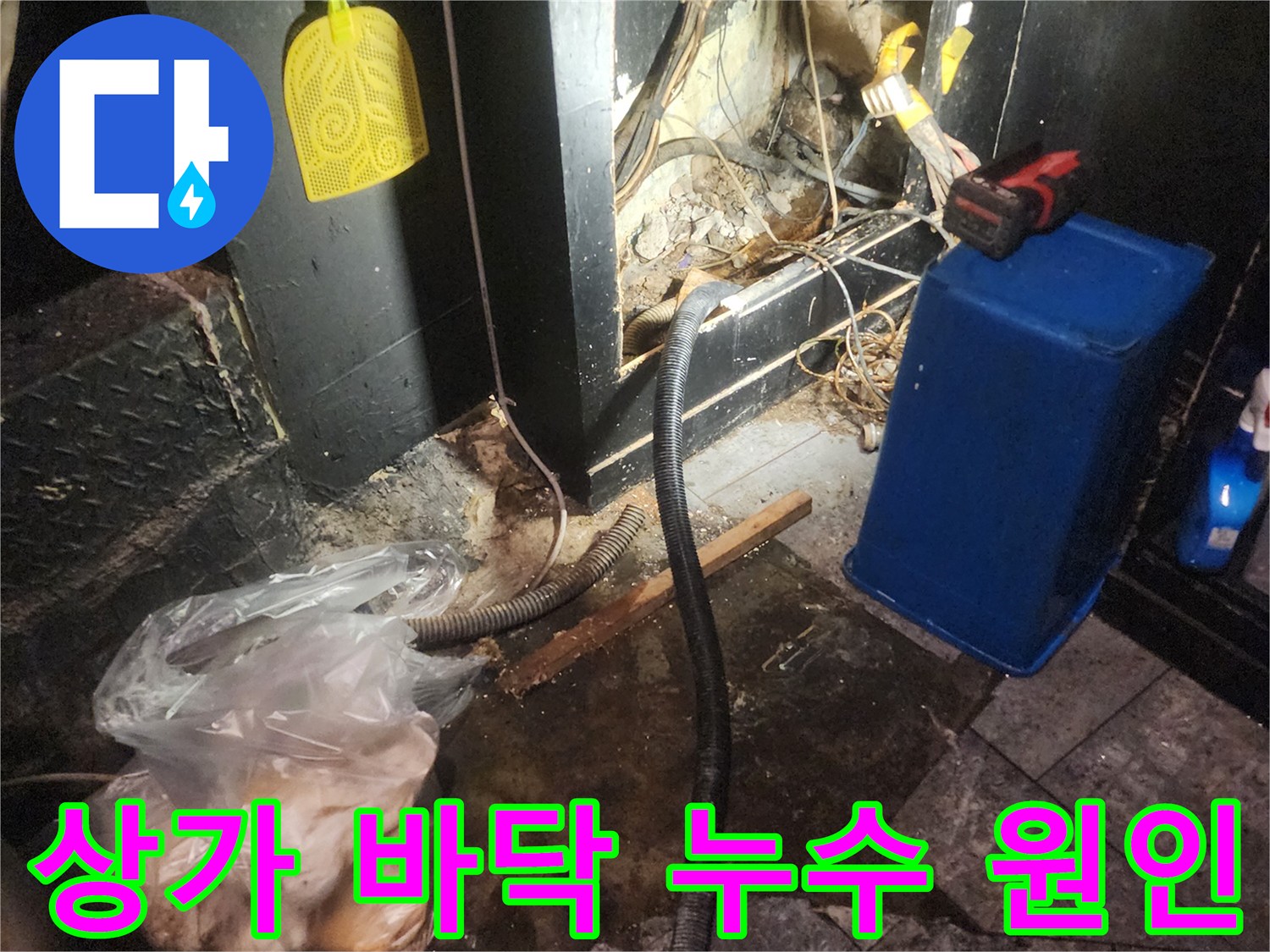 어두운 상가 바닥 아래에서 복잡하게 얽힌 배관과 전선-그리고 물이 새는 흔적을 보여주는 누수 탐지 현장 이미지