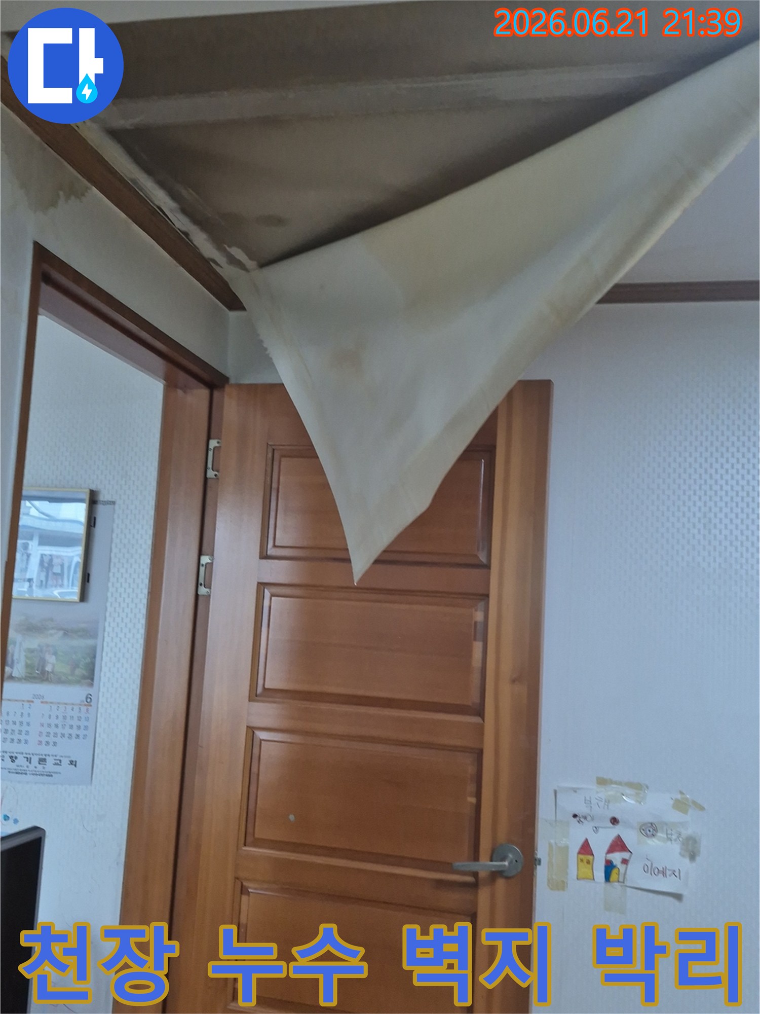 천장 벽지가 물에 젖어 한쪽 모서리부터 심하게 박리되어-아래로 축 늘어진 모습이 담긴 사진