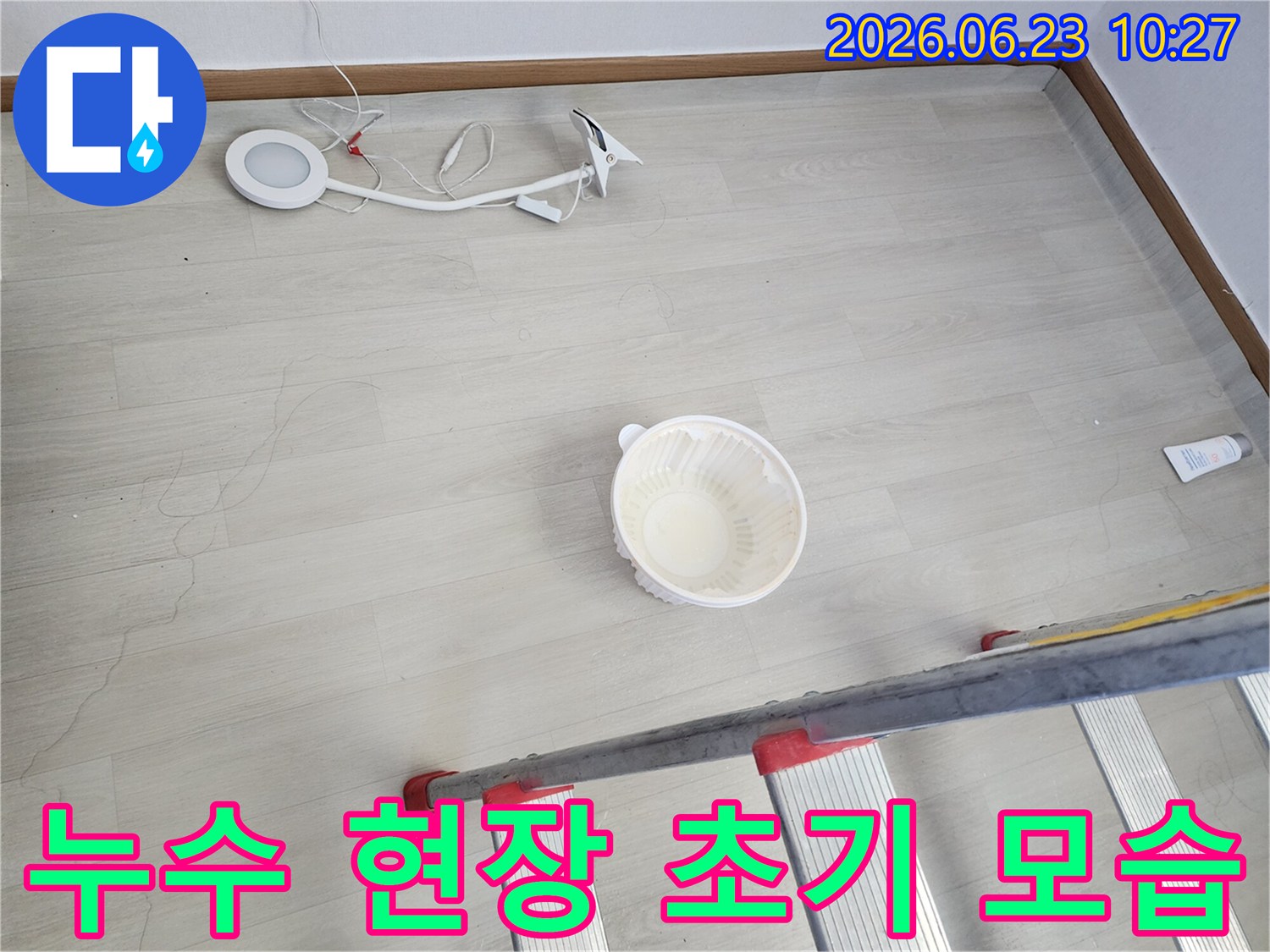 천장에서 물이 떨어져 바닥에 놓인 물받이 그릇과-누수 지점 확인을 위한 사다리-작업용 조명 장비가 함께 보이는-누수 공사 전 현장 모습입니다