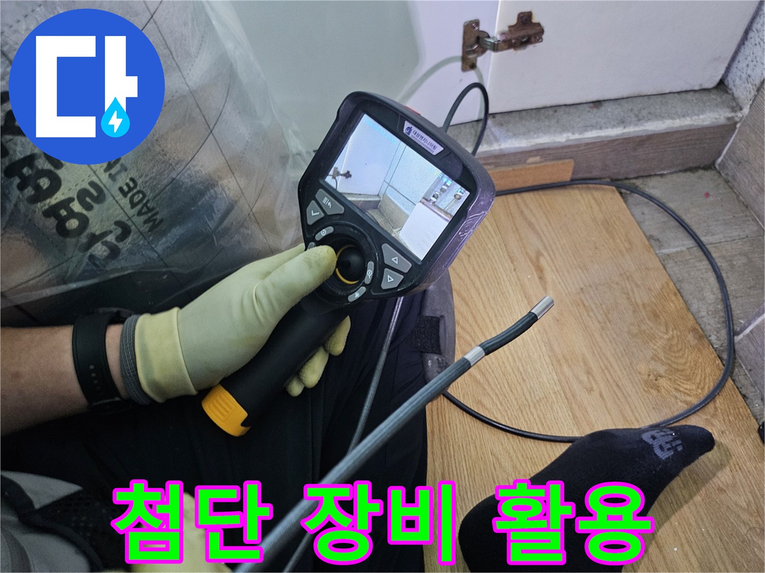 이 이미지는-숙련된 기술자가-누수 문제를 해결하고자-내시경 탐지기로-숨겨진 배관의 상태를 확인하는 과정입니다.