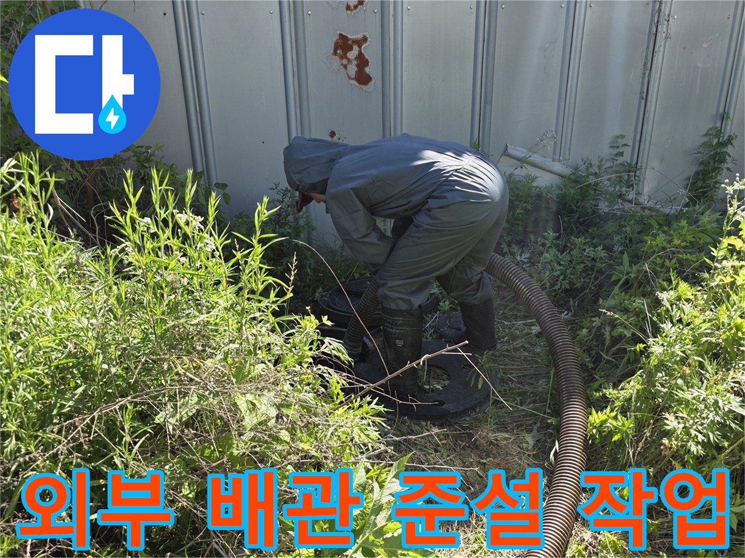 배관 내부의 오물을 제거하기 위해 외부 맨홀에 호스를 투입하는 장면입니다.