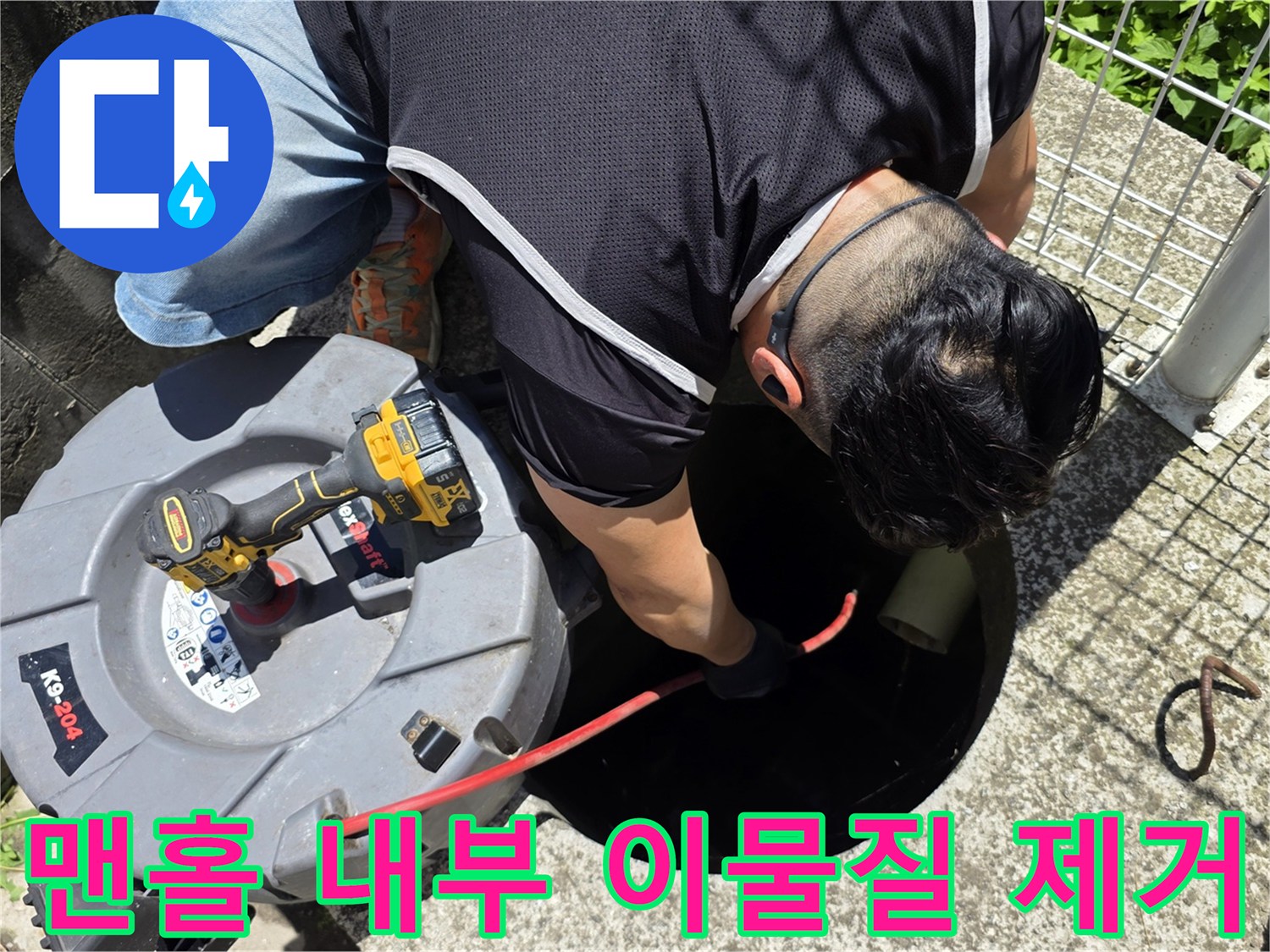 오수 맨홀 입구에서 배관 청소를 위해 장비를 투입하는 장면