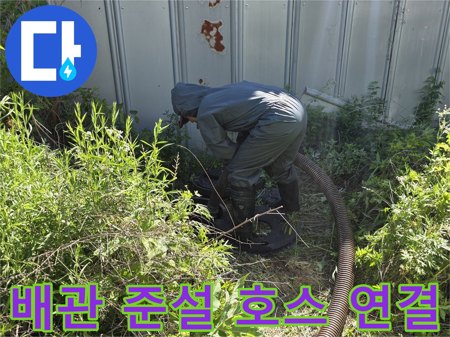 풀숲 사이 맨홀에 설치된-준설 차량용 흡입 호스