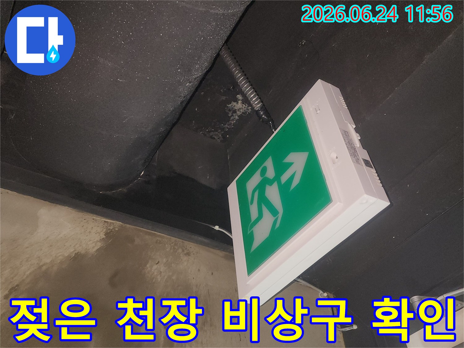 건물 천장에서 발생한 물샘 현장을-비상구 등기구와 함께 촬영한 이미지입니다