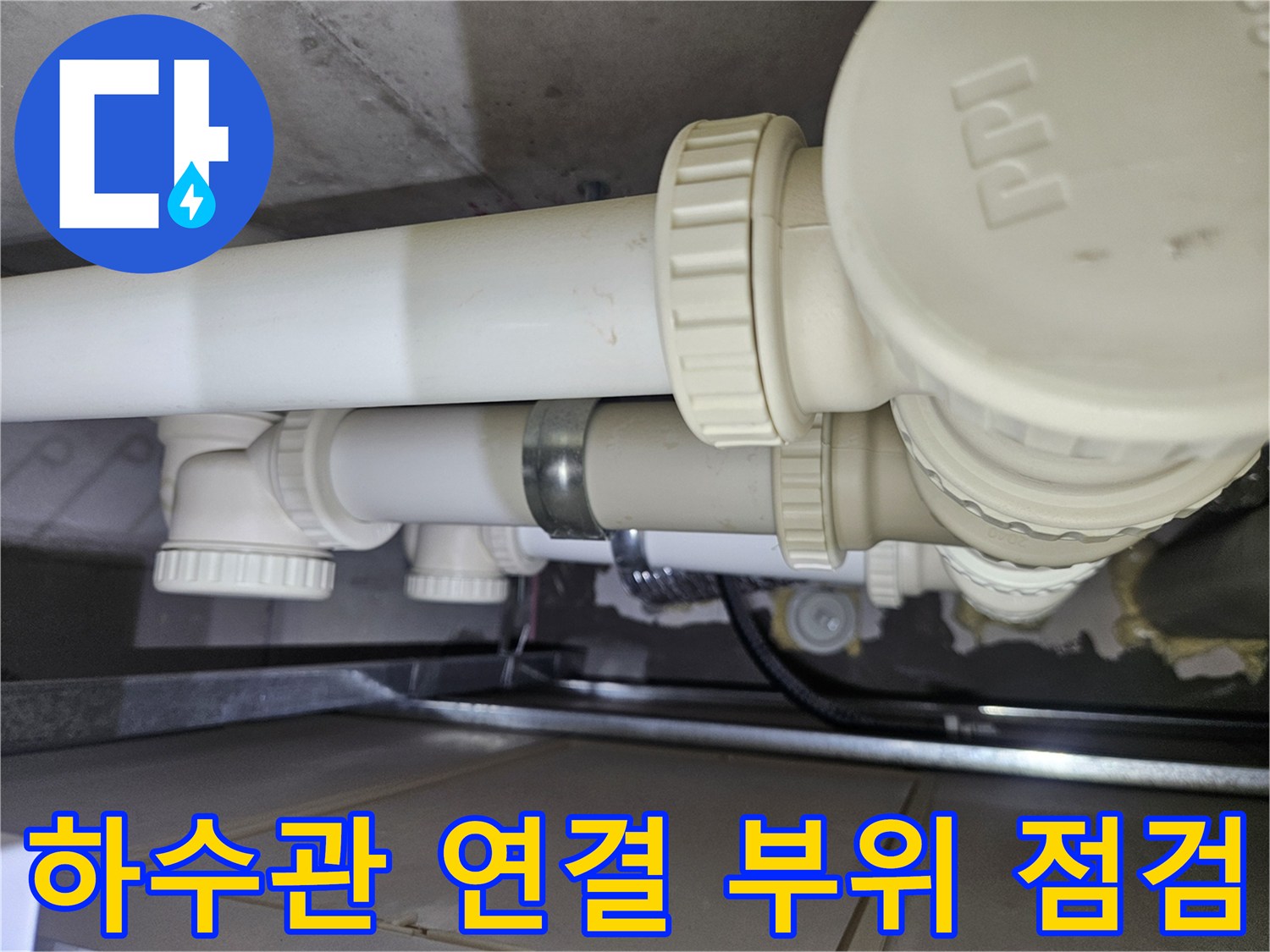 천장에 노출된 하얀색 PVC 배관과 연결 소켓의 근접 촬영본입니다.