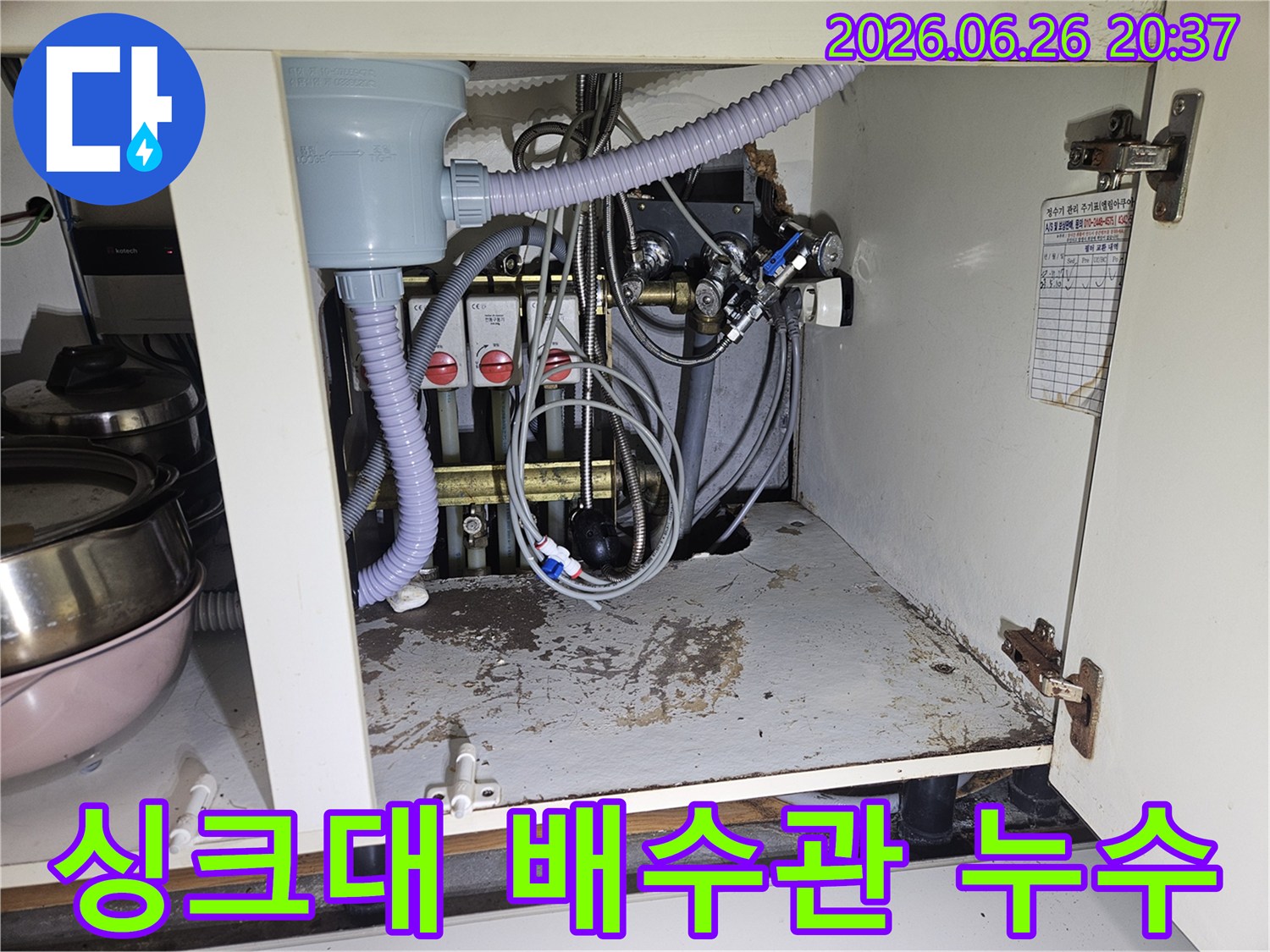 싱크대 하부 캐비닛 안-오래된 배수관 연결 부위에서 물이 새어 바닥에 얼룩을 만든 모습