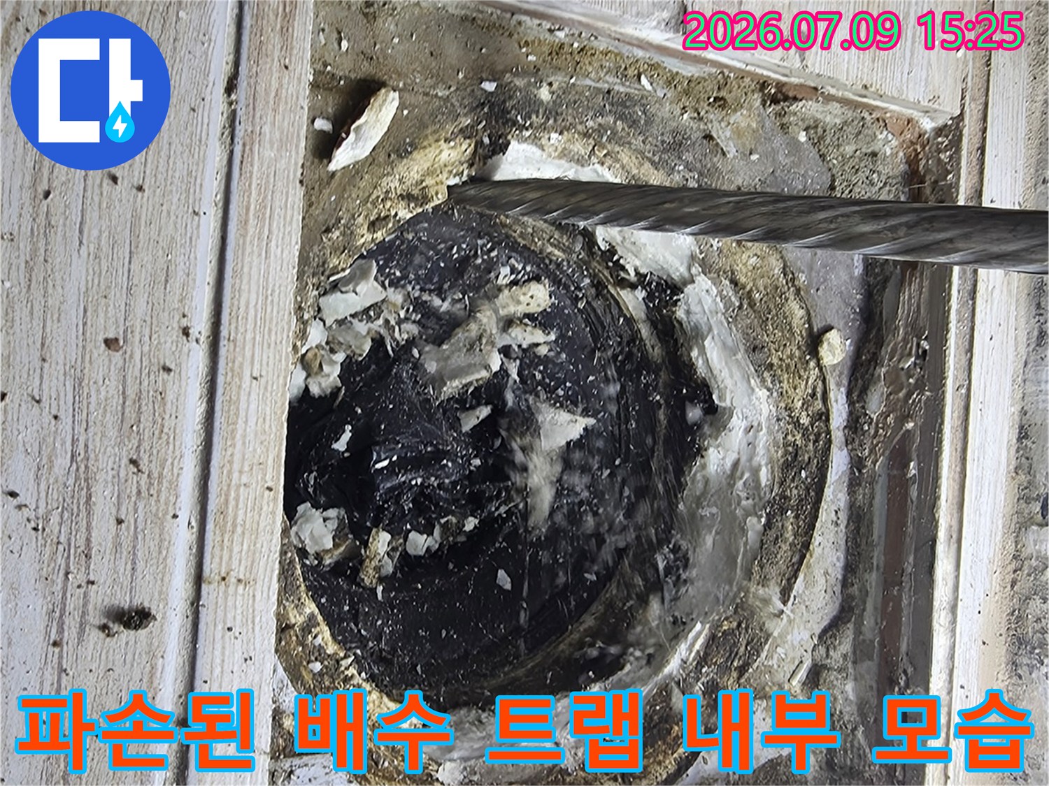 세탁실 바닥 내부에 노출된 파손된 배수구와 주변의 오염물질