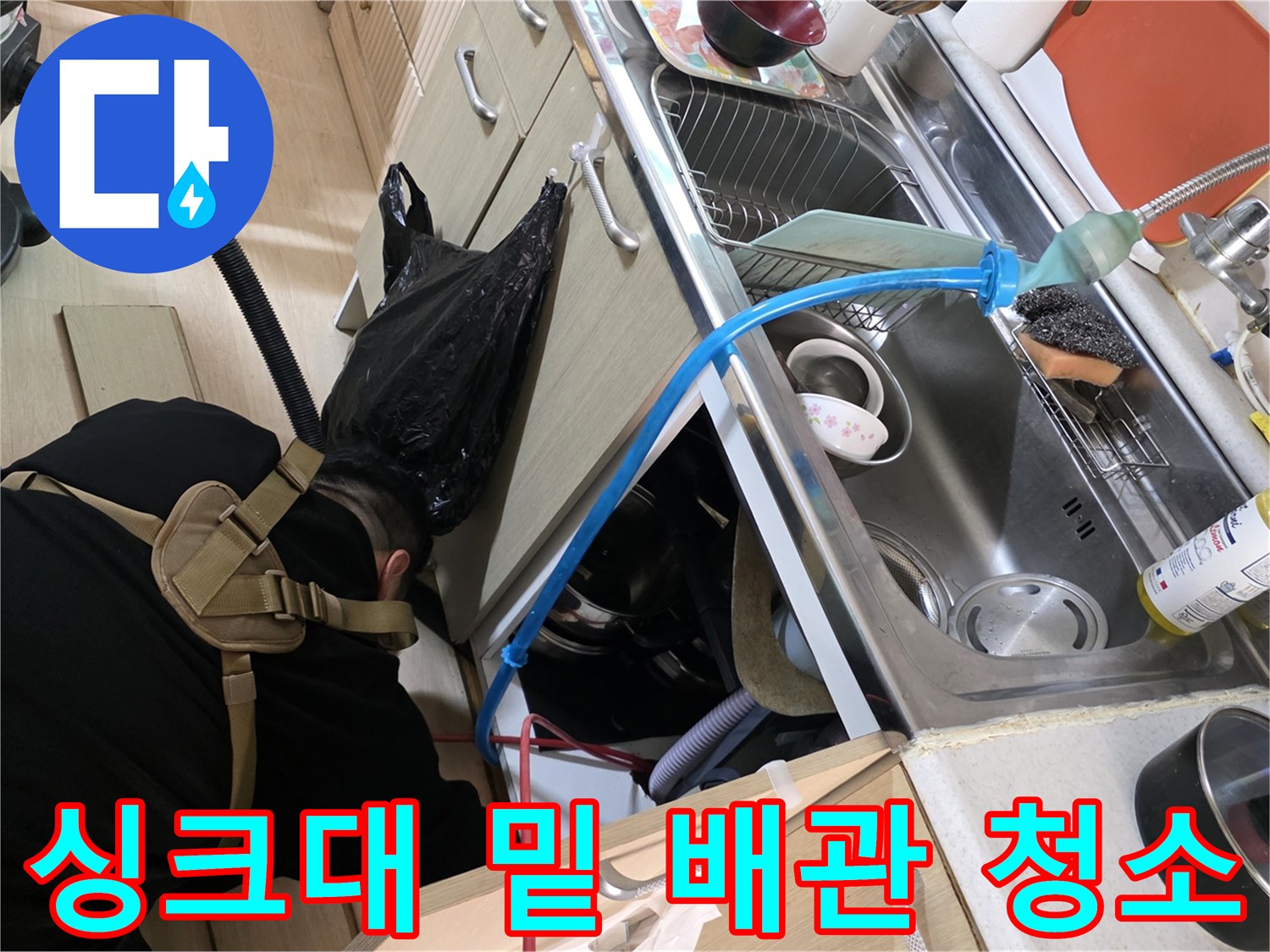 배수 호스 주변의 물기를 제거하기 위해 습식 청소기를 사용하는 모습
