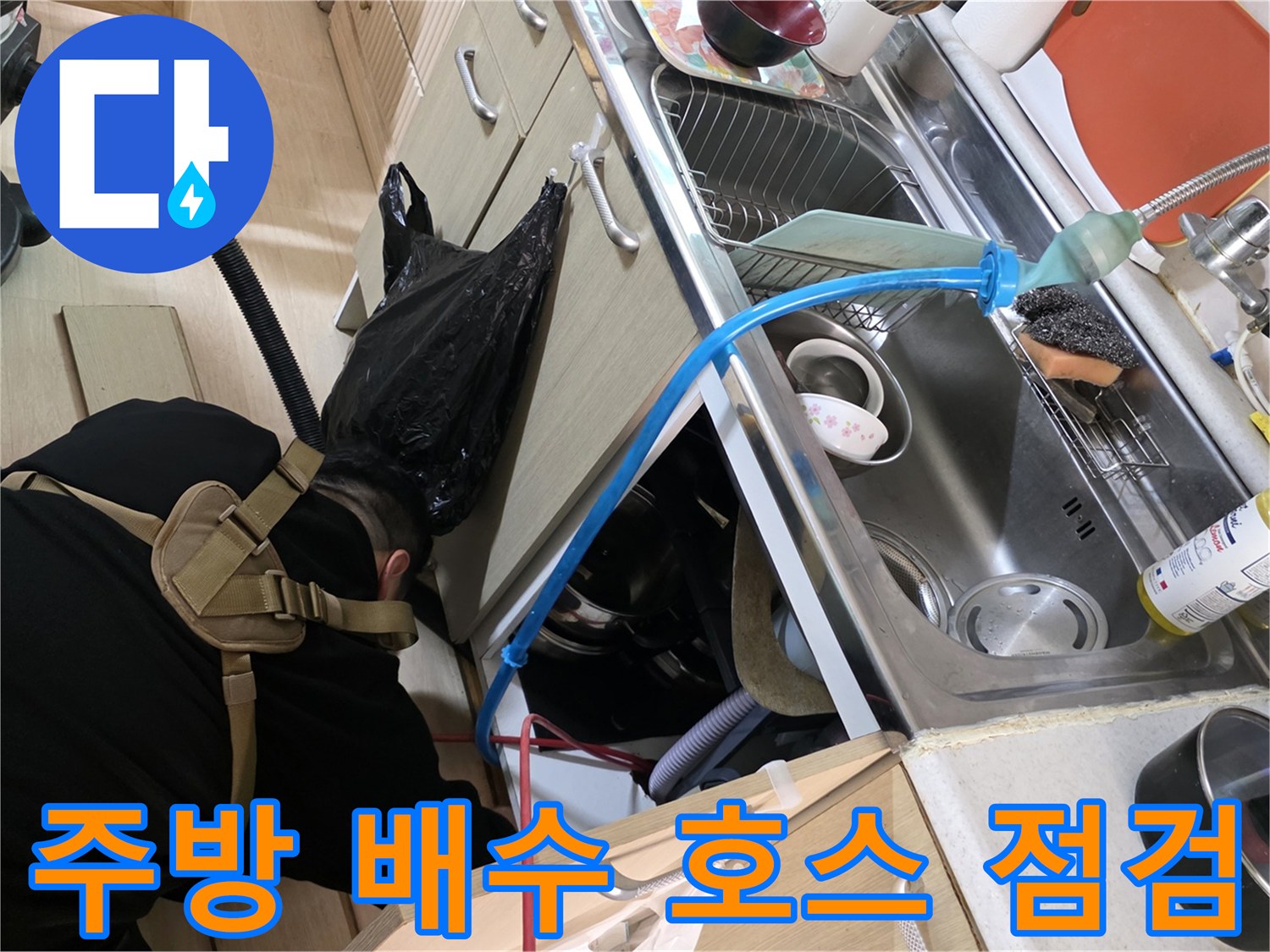 싱크대 하단 파란색 배수 호스와 주변 배관의 누수 여부를 확인하는 모습