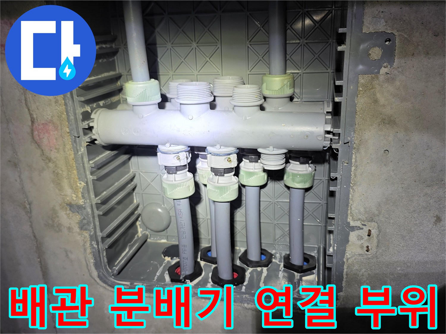 벽면에 설치된 배관 분배기의 회색 연결 부속들을 보여주는 사진입니다.
