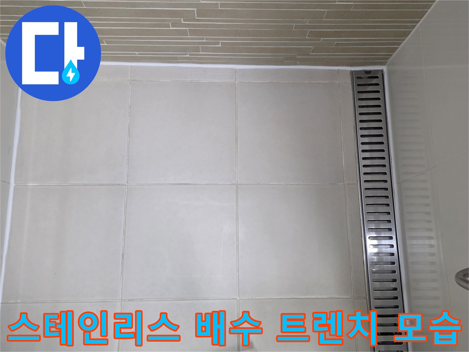 바닥 타일과 연결된 스테인리스 재질의 배수 트렌치 근접 사진