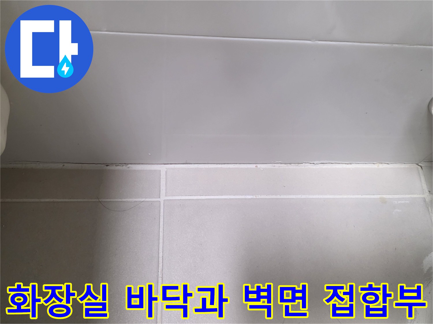 하얀색 타일과 금속 배관 연결 부위의 클로즈업 사진