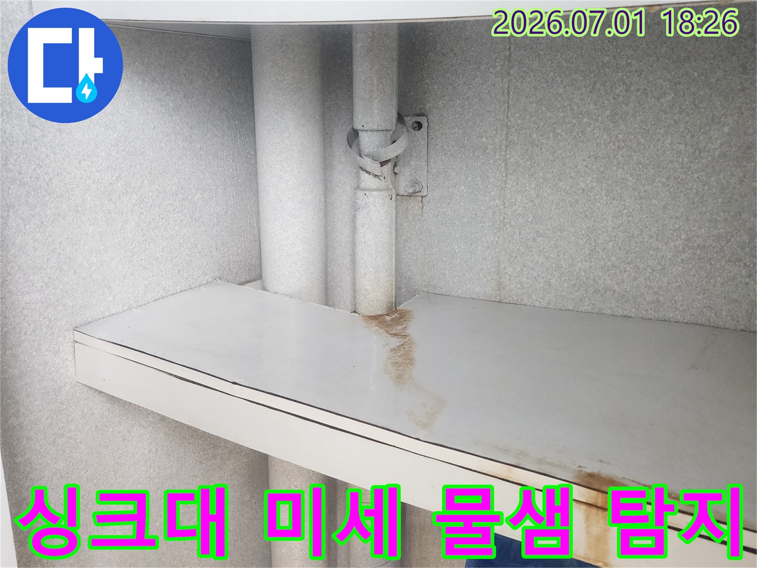 이 이미지는-싱크대 하부-배관 주변-가구 패널에-나타난-미세한 물 자국을 통해-숨겨진 누수를-탐지하는-현장을 보여줍니다