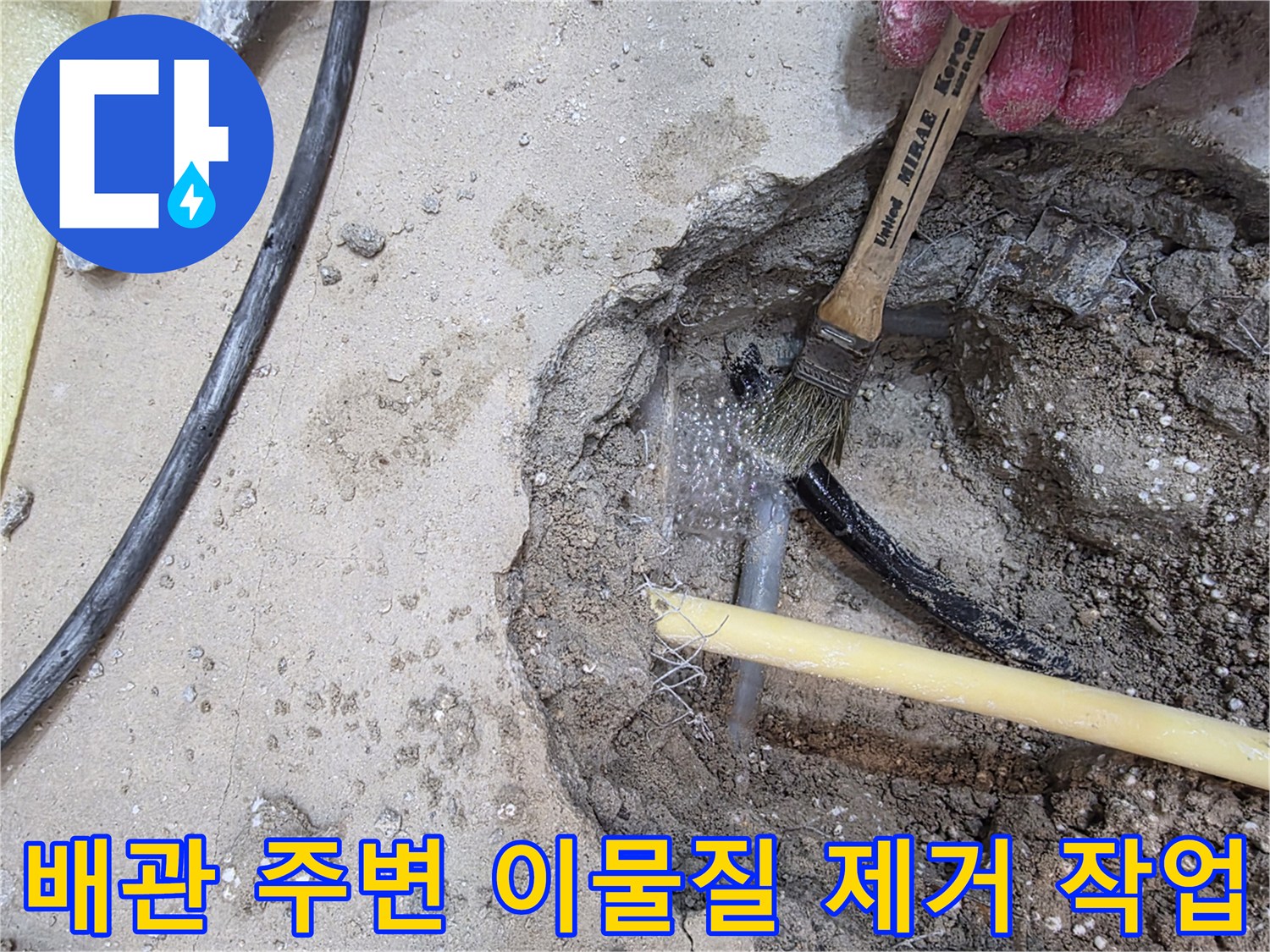 브러시를 사용하여-노출된 배관 주위의 흙을 털어내는 모습
