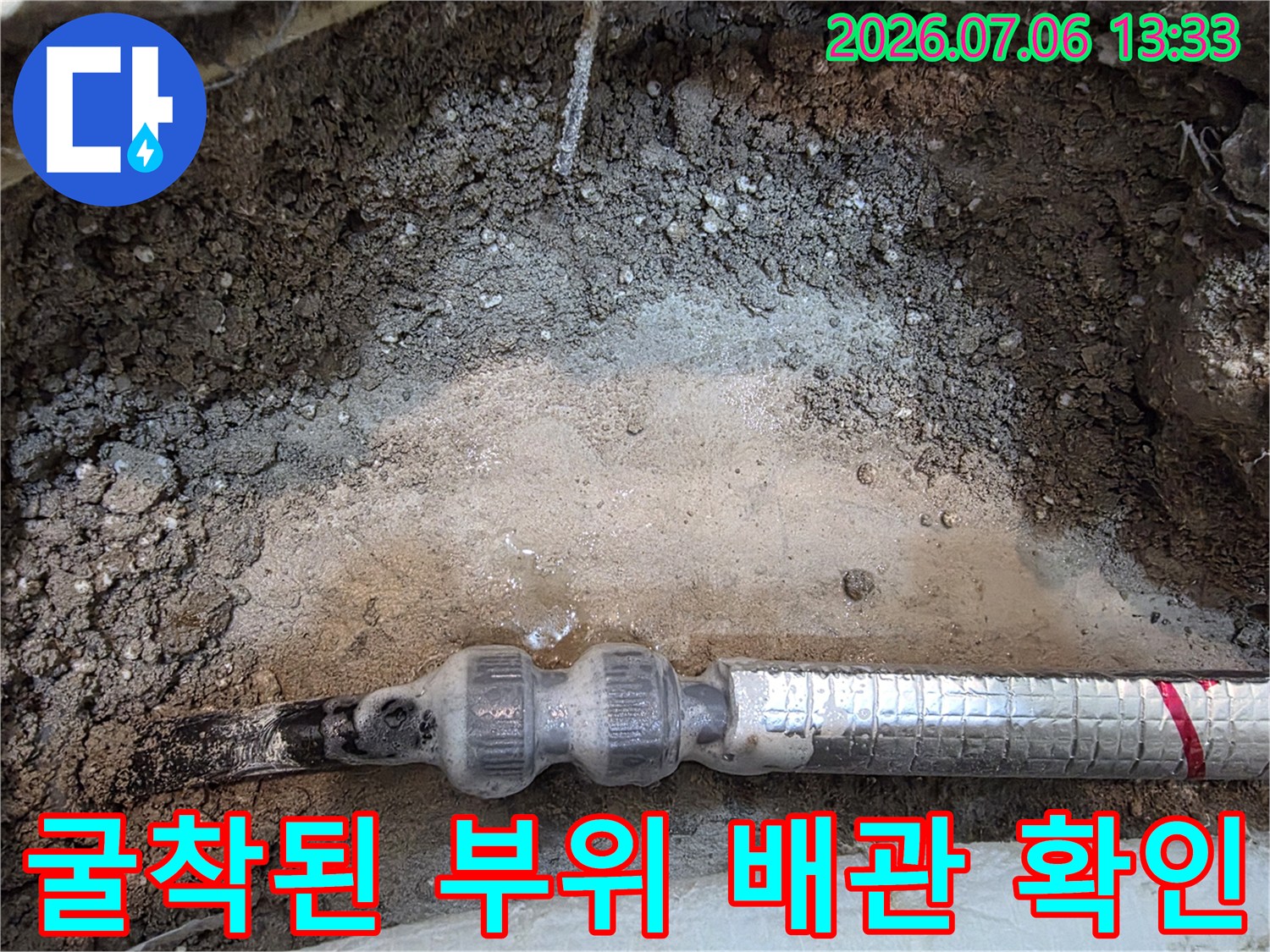 흙을 파내고 노출시킨 은색 보온재 덮인 배관의 수리 상태