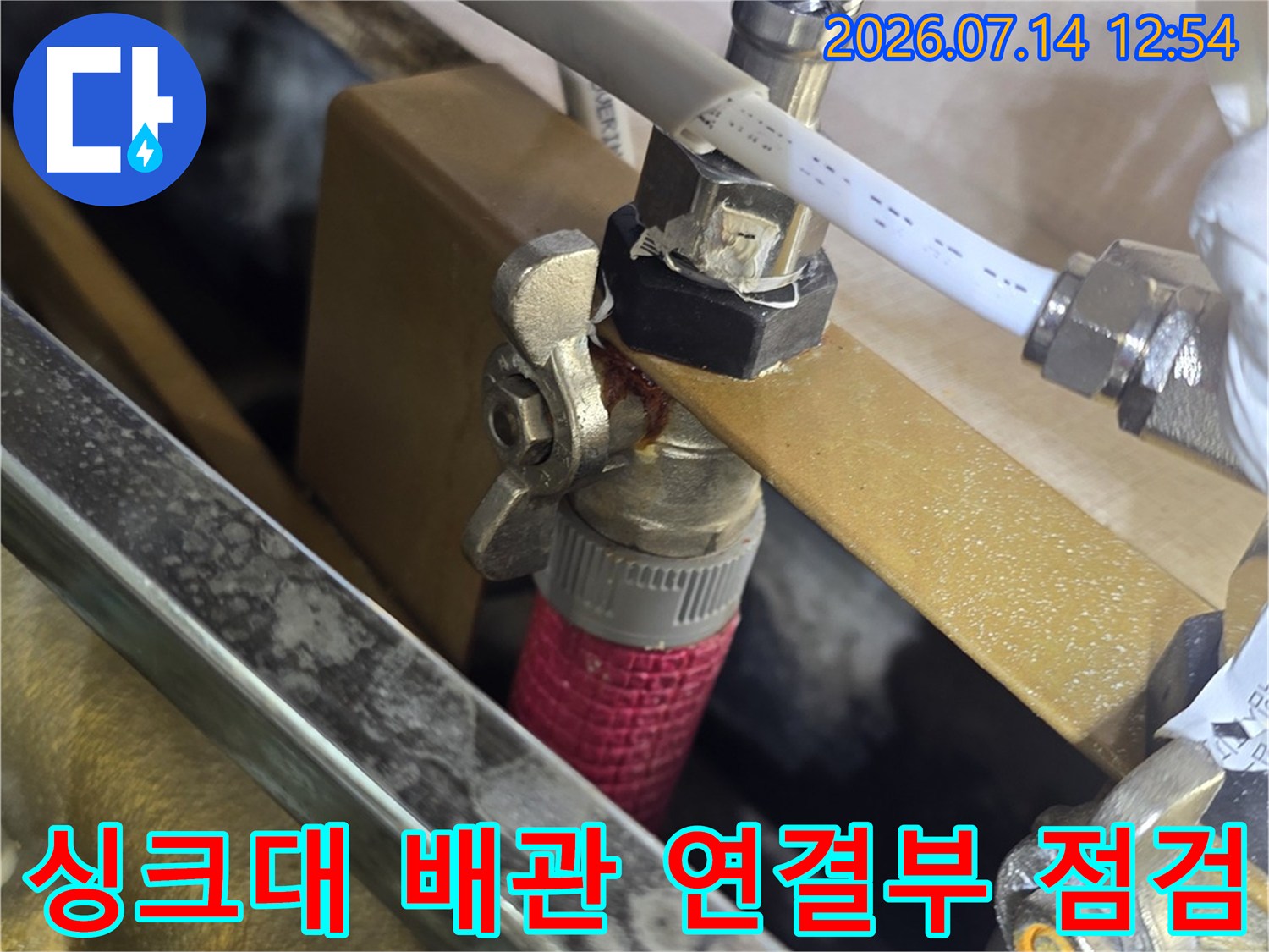 싱크대 하부 배관 부속과 노출된 배관 연결부를 정밀하게 점검하는 모습
