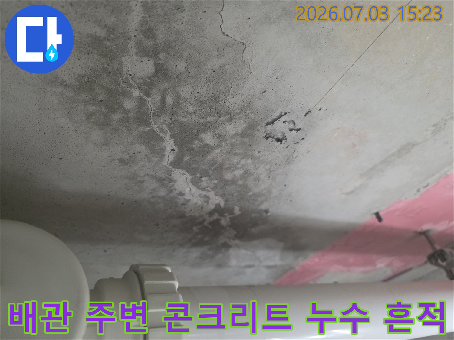 노출된 배관과 그 주변으로 번진 짙은 색의 수분 침투 얼룩이 있는 천장면