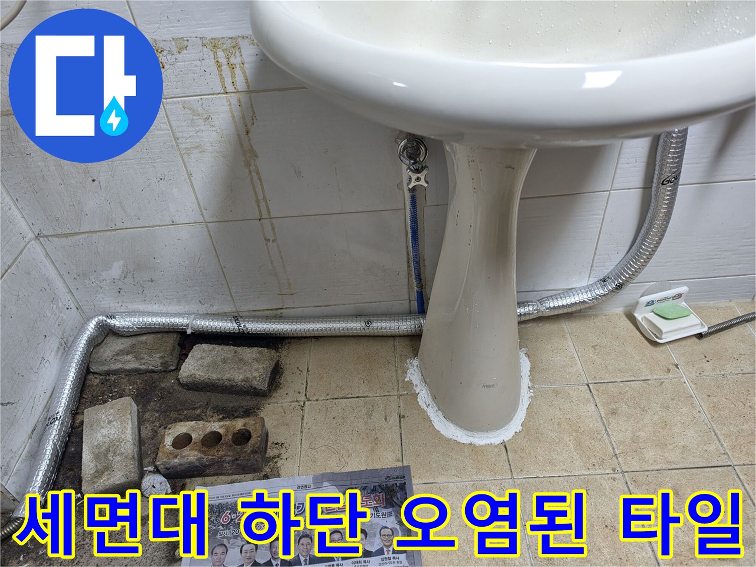세면대 아래쪽 벽면의 변색된 타일과 배관 연결 상태를 보여주는 사진입니다.