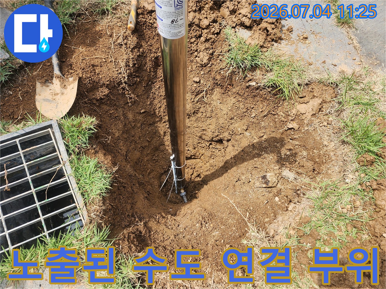 파헤쳐진 흙 속에서 드러난 수도 배관과 작업용 삽이 있는 모습