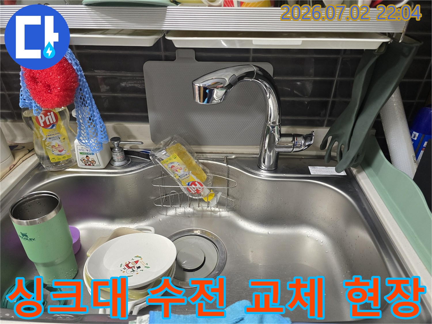 스테인리스 싱크대에 설치된 새 수전과 세척용품이 놓인 모습