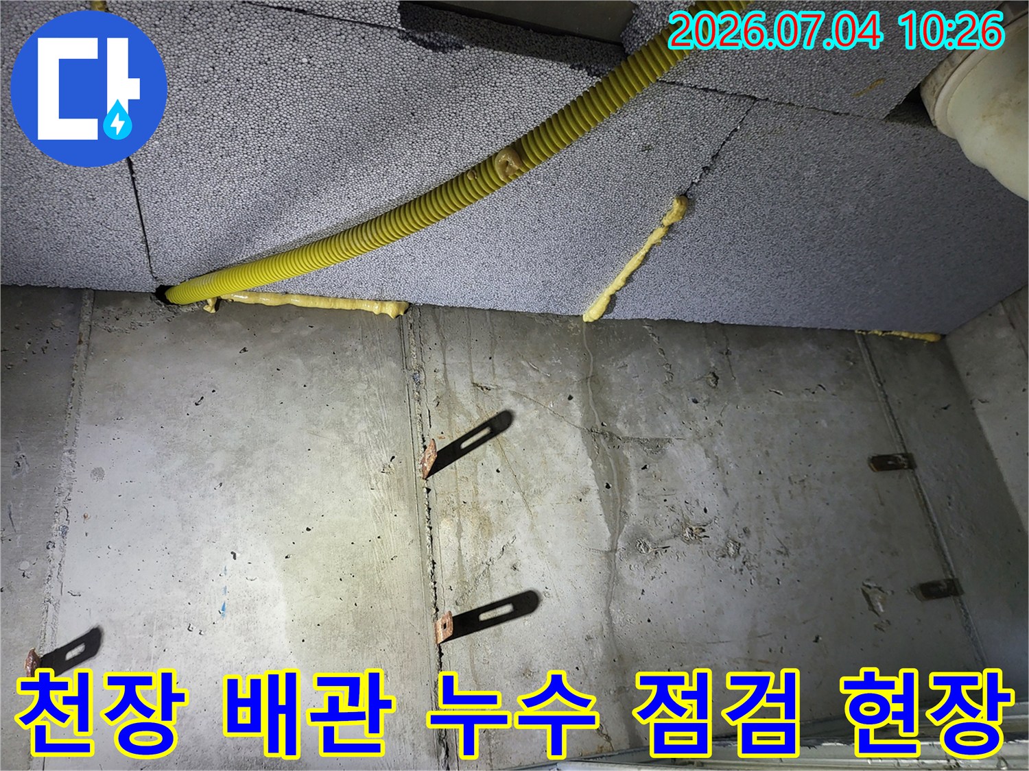 노란색 보호재가 씌워진 화장실 천장 내부 배관과 마감면을 촬영한 사진