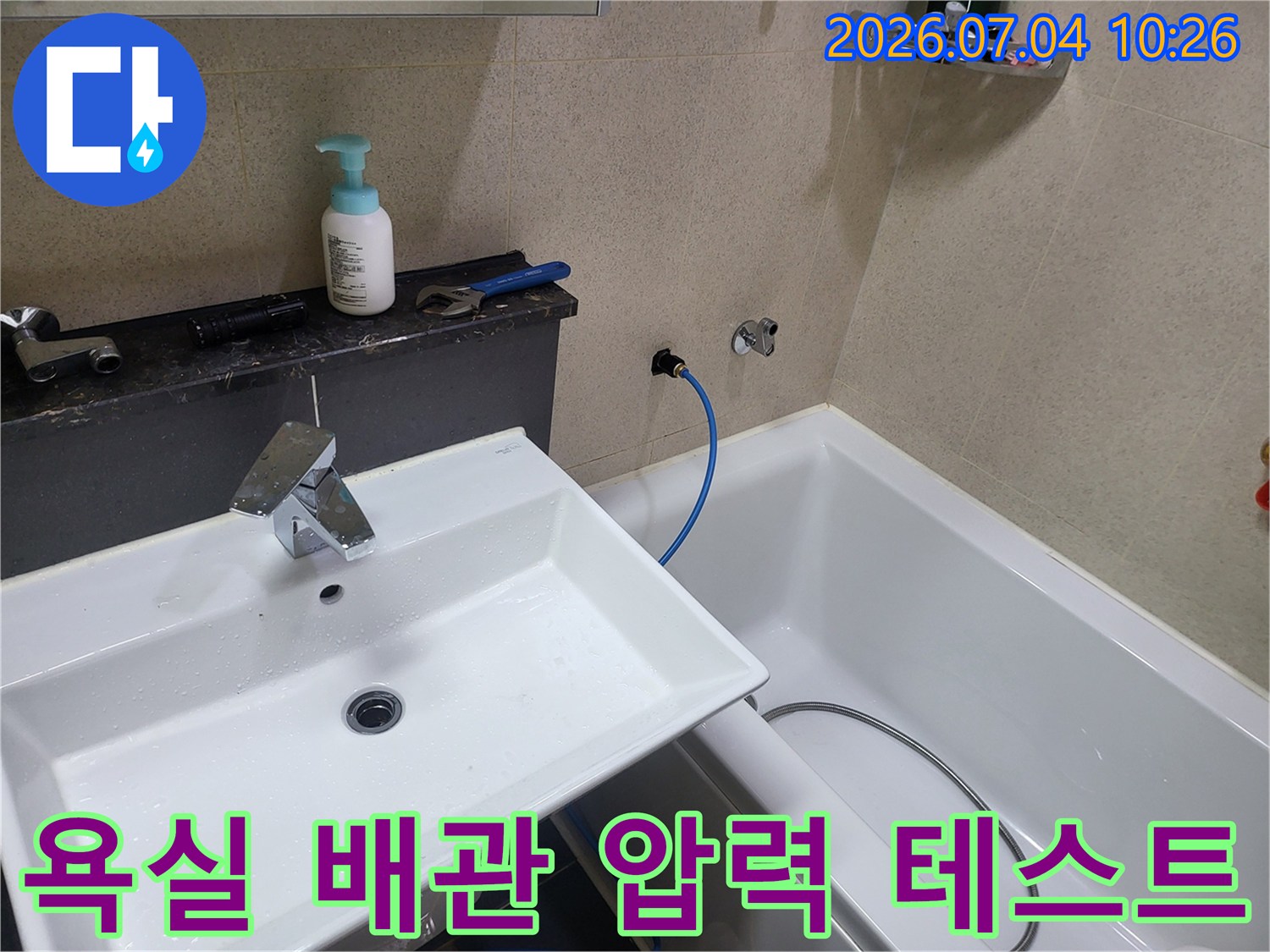 세면대 옆 수도 배관에 연결된 호스를 통해 공압을 체크하는 전문 장비 세팅 모습