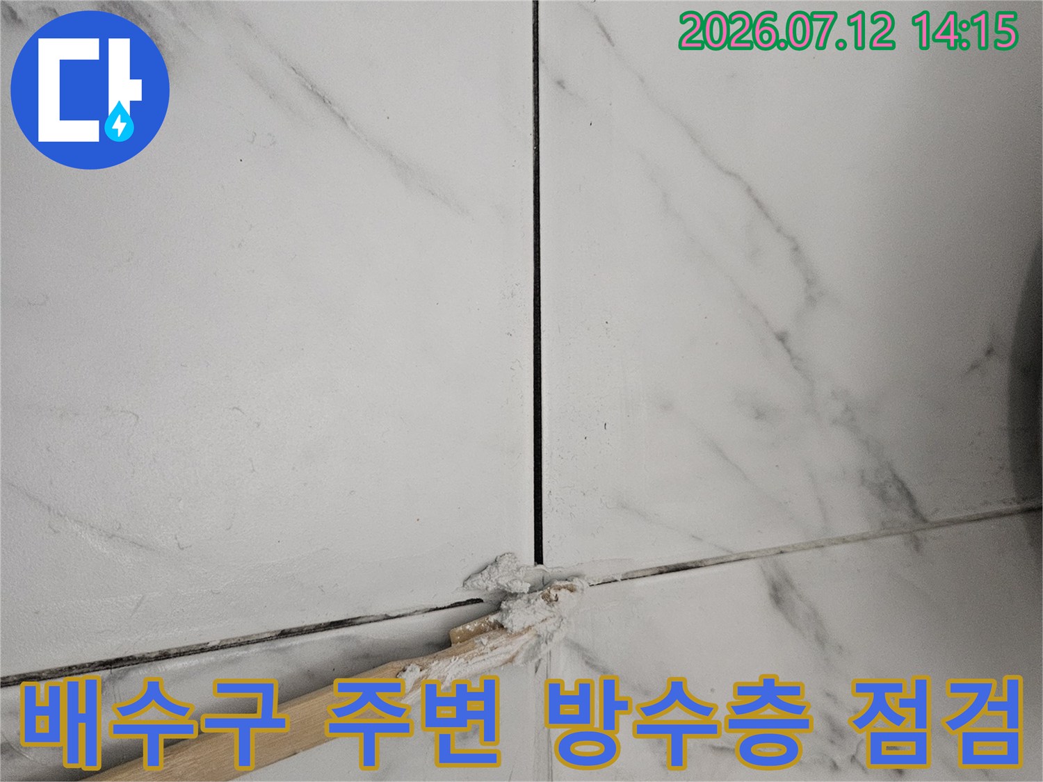 배수구가 위치한 타일 경계부의 노후 상태와 균열을 조사하는 현장 사진