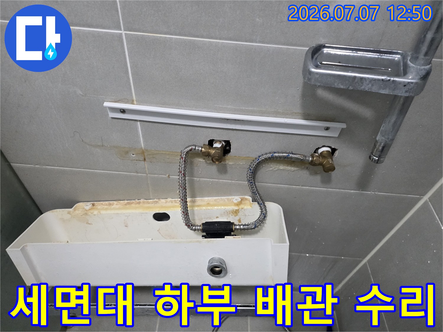 세면대와 연결된 노출 배관 호스 및 밸브 부위 수리 장면