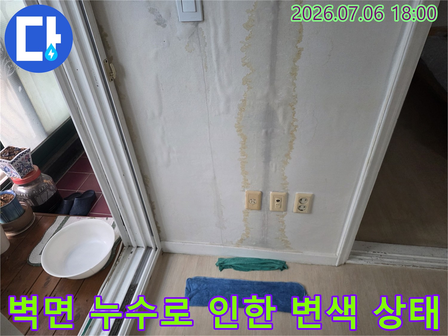 벽면에 수직으로 발생한 황체색의 대형 습기 얼룩과 벽면 콘센트 위치