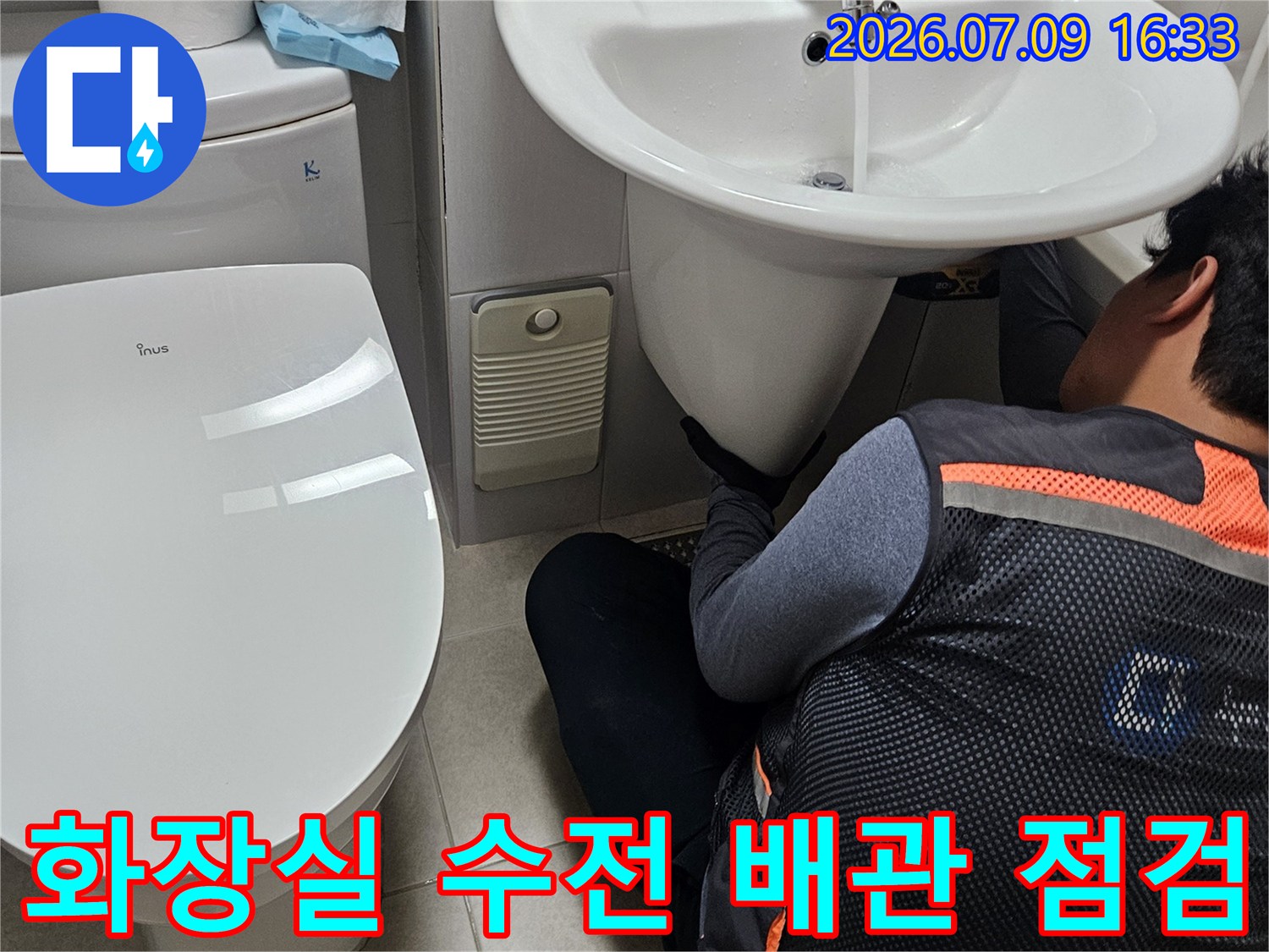 세면대 아래 공간에서 작업자가 정밀하게 배관을 살피는 장면