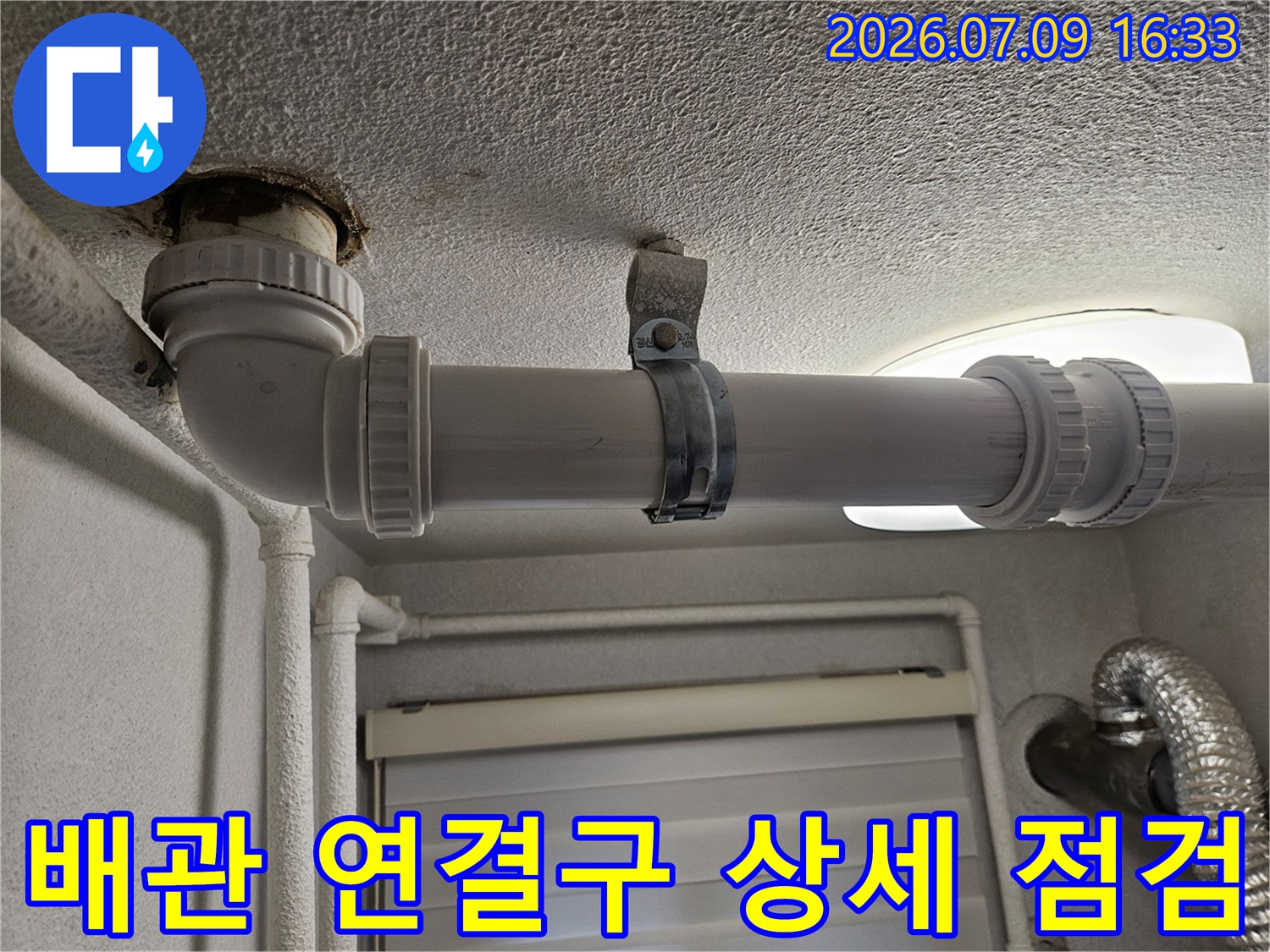 천장 내부 배관 연결 부위와 고정 클램프가 노출된 장면