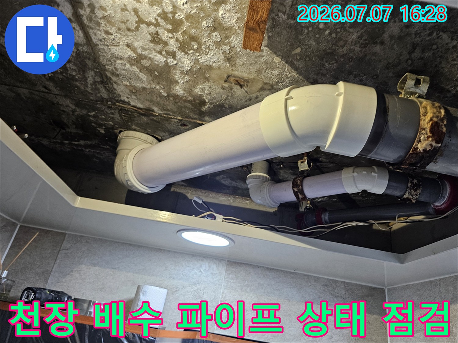거친 콘크리트 천장면에 설치된 노후한 배수용 하얀색 파이프의 상세 모습