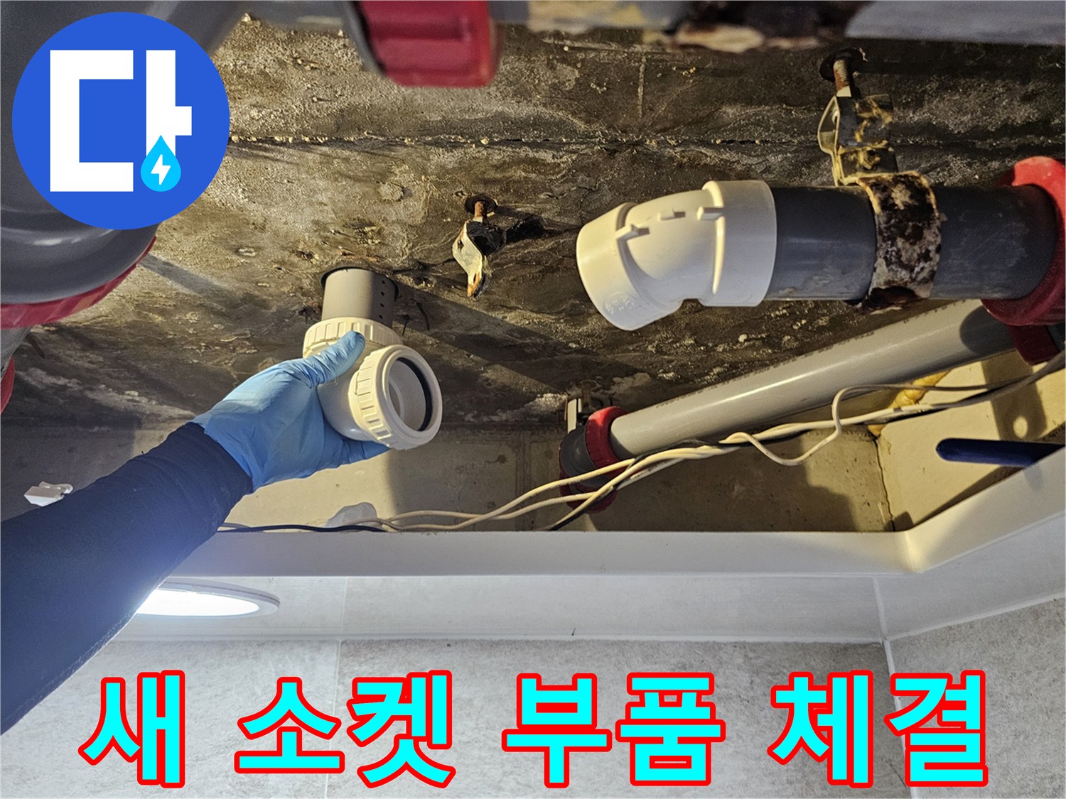 푸른색 장갑을 낀 작업자가 배관 부속을 교체하는 모습