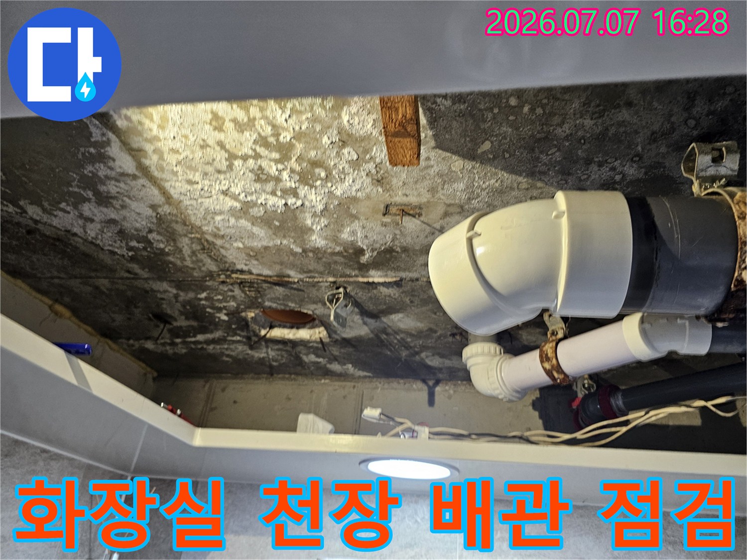 화장실 천장 내부의 노출된 하얀색 배수 배관과 주변 콘크리트 상태