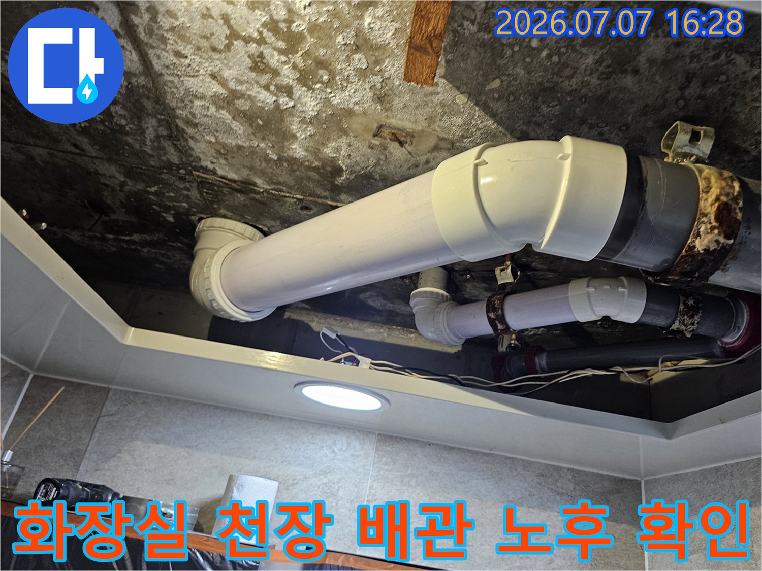 화장실 천장 안쪽의 노후된 배수 배관과 연결 부위 상태를 촬영한 사진