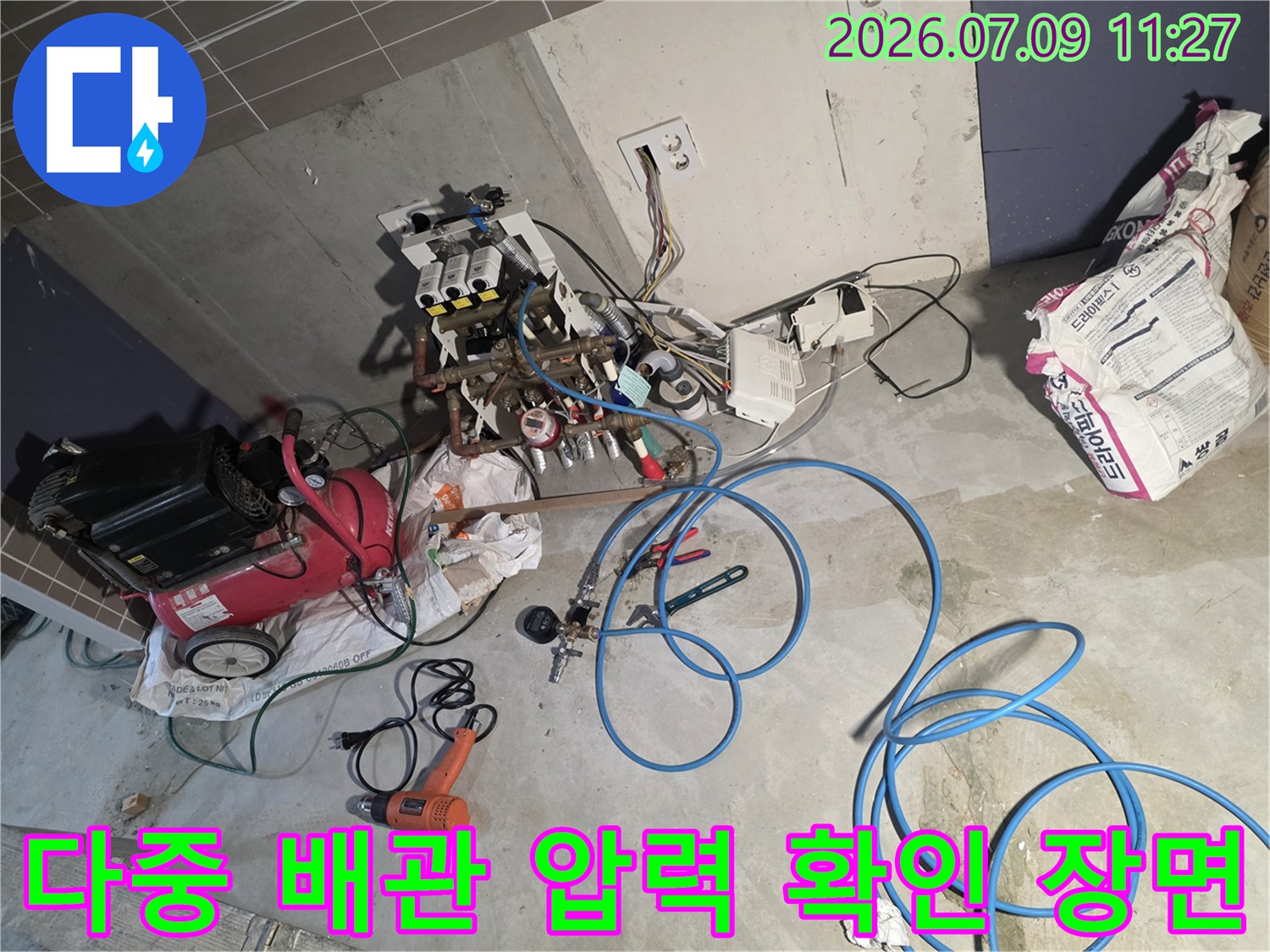 분배기 연결 부위에 공압 호스를 연장하여 신규 설치된 배관의 기밀성을 테스트하는 모습