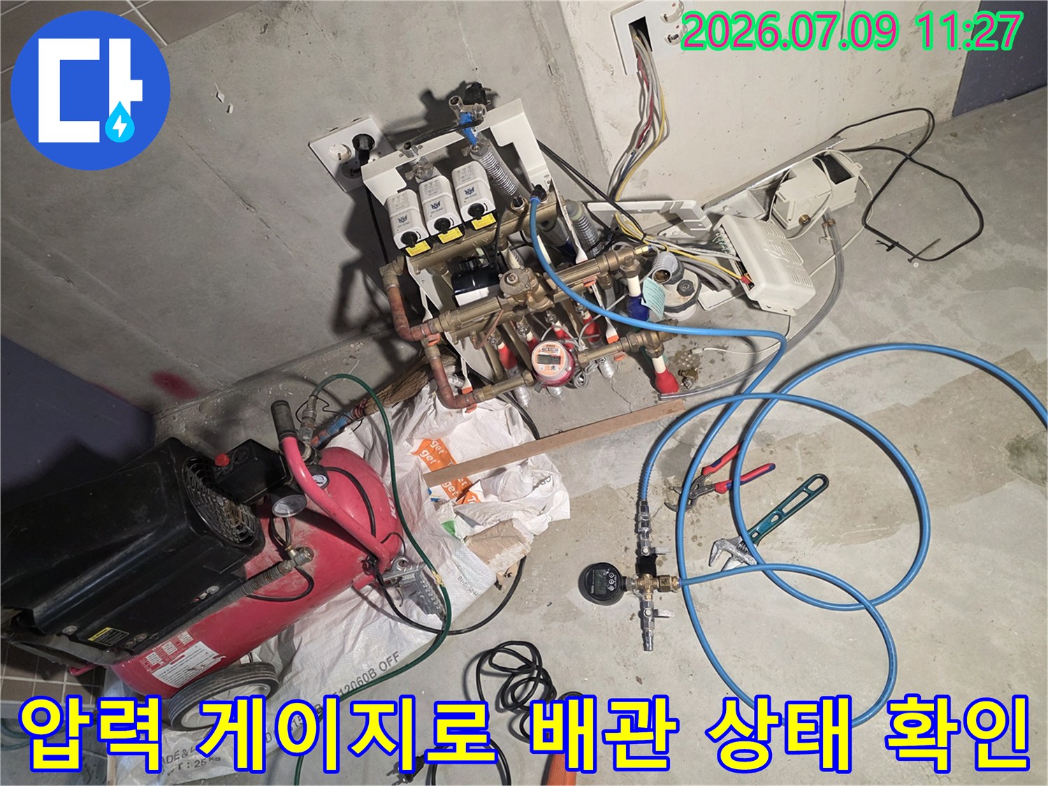 파란색 호스와 압력계가 연결된 분배기 시스템을 통해 신용 배관의 기밀성을 검증하는 작업 현장