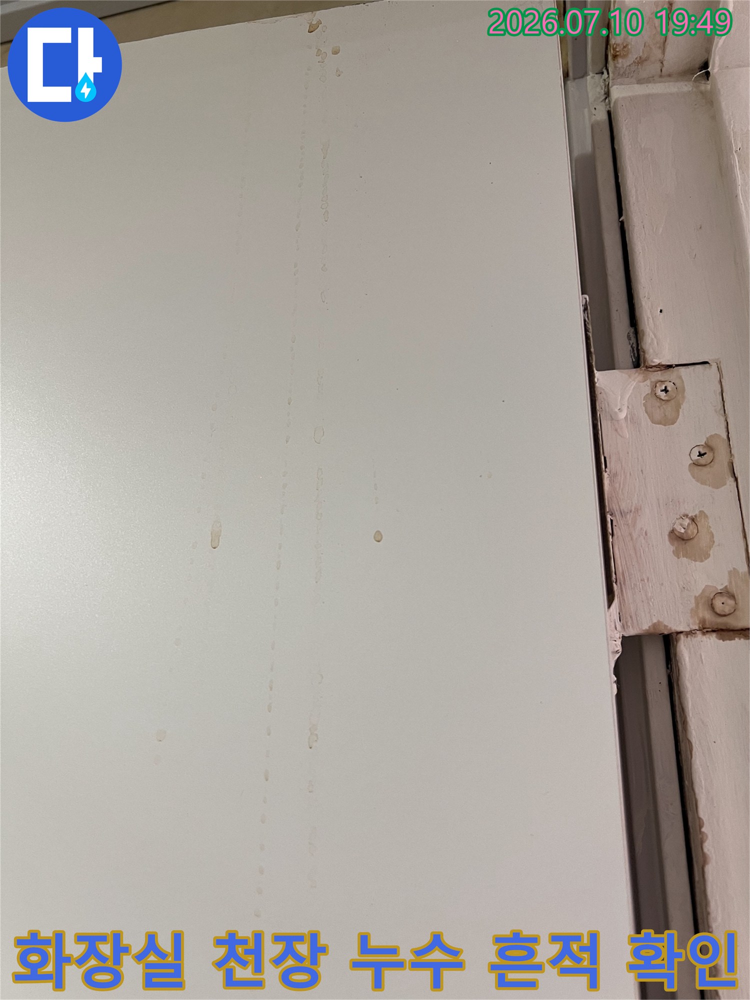 흰색 화장실 천장재에 남은 갈색 물자국과 배관 주변의 습기 흔적