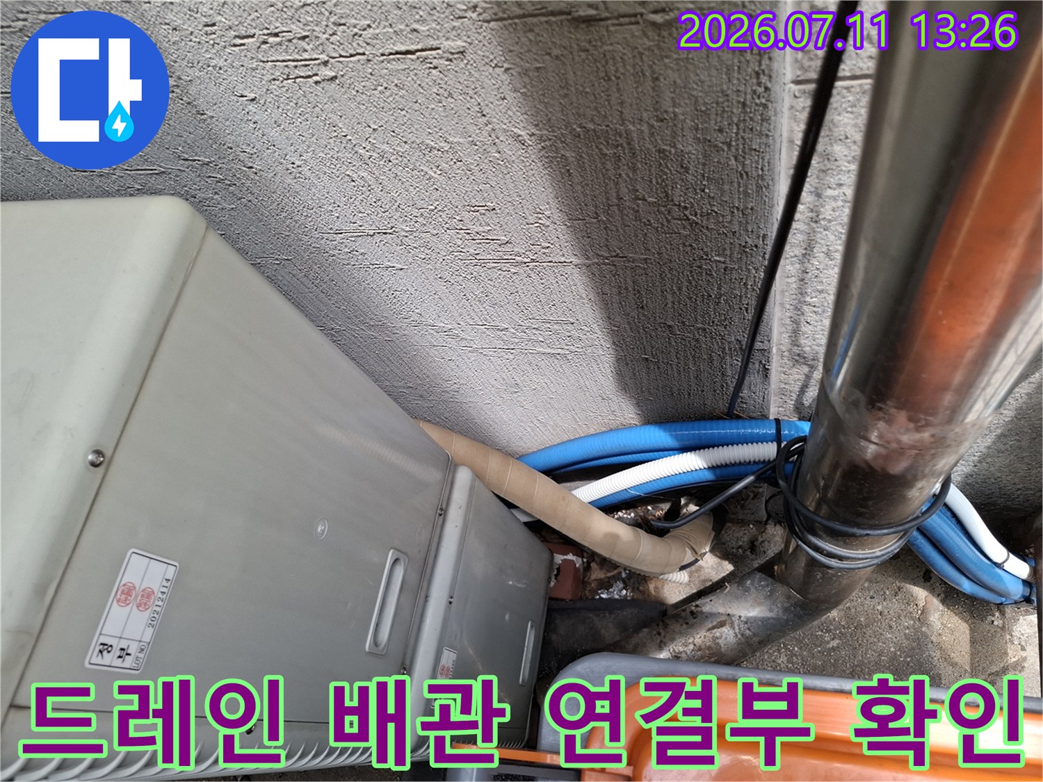 노출된 에어컨 드레인 배관과 주변 관로의 연결 상태를 점검하는 모습