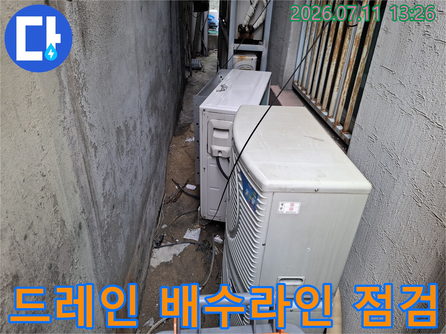 실외기 주변의 노후된 드레인 배관과 연결부를 세밀하게 조사하는 현장 사진