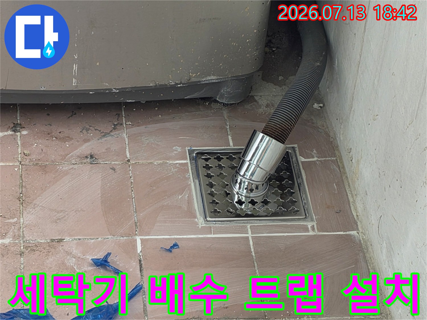 세탁실 바닥에 설치된 스테인리스 배수구와 연결된 세탁기 호스